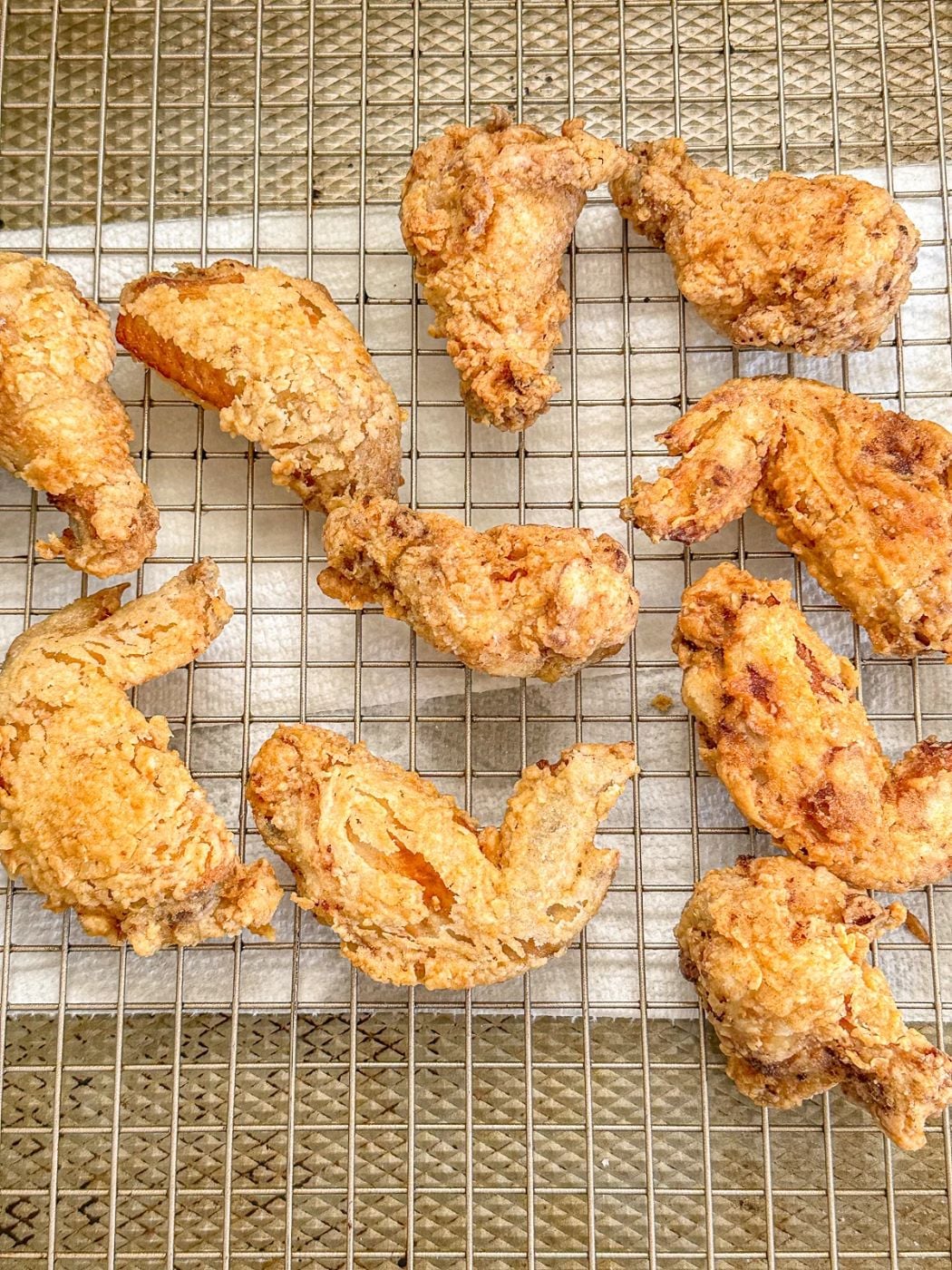 Putting fried chicken wings on a wire rack.
