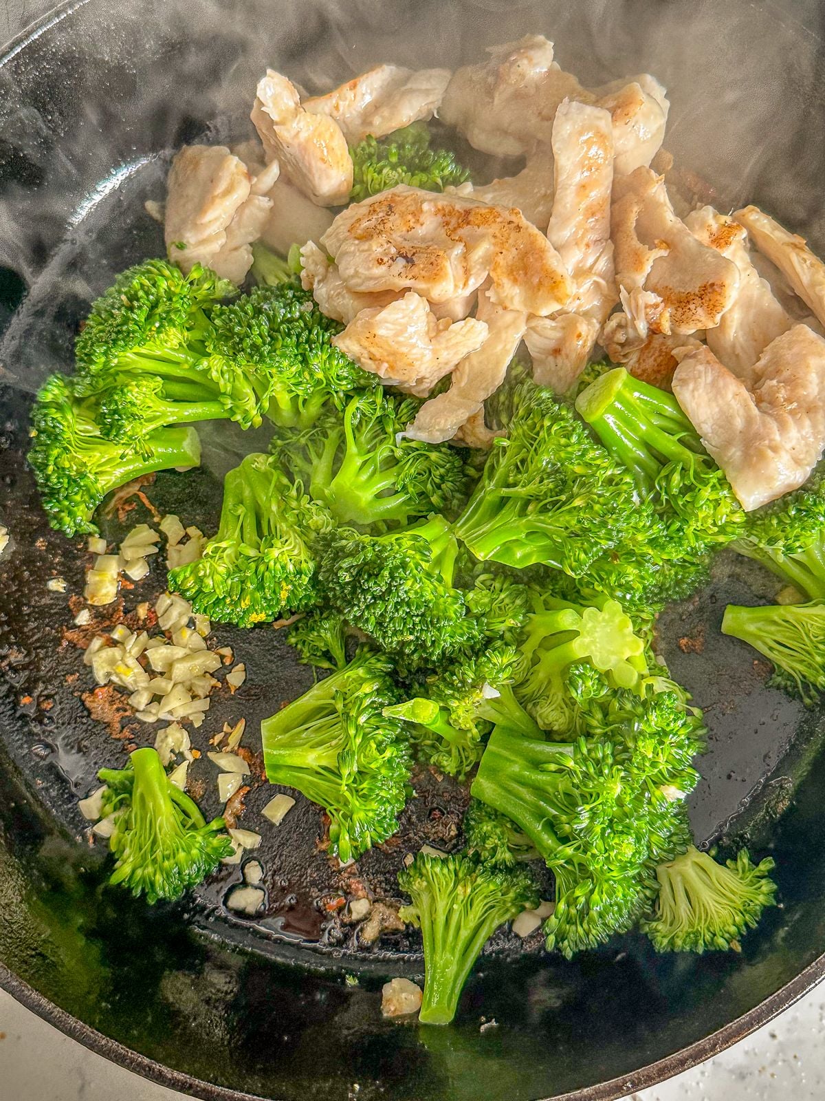 Frying chicken, broccoli and minced garlic in a pan.