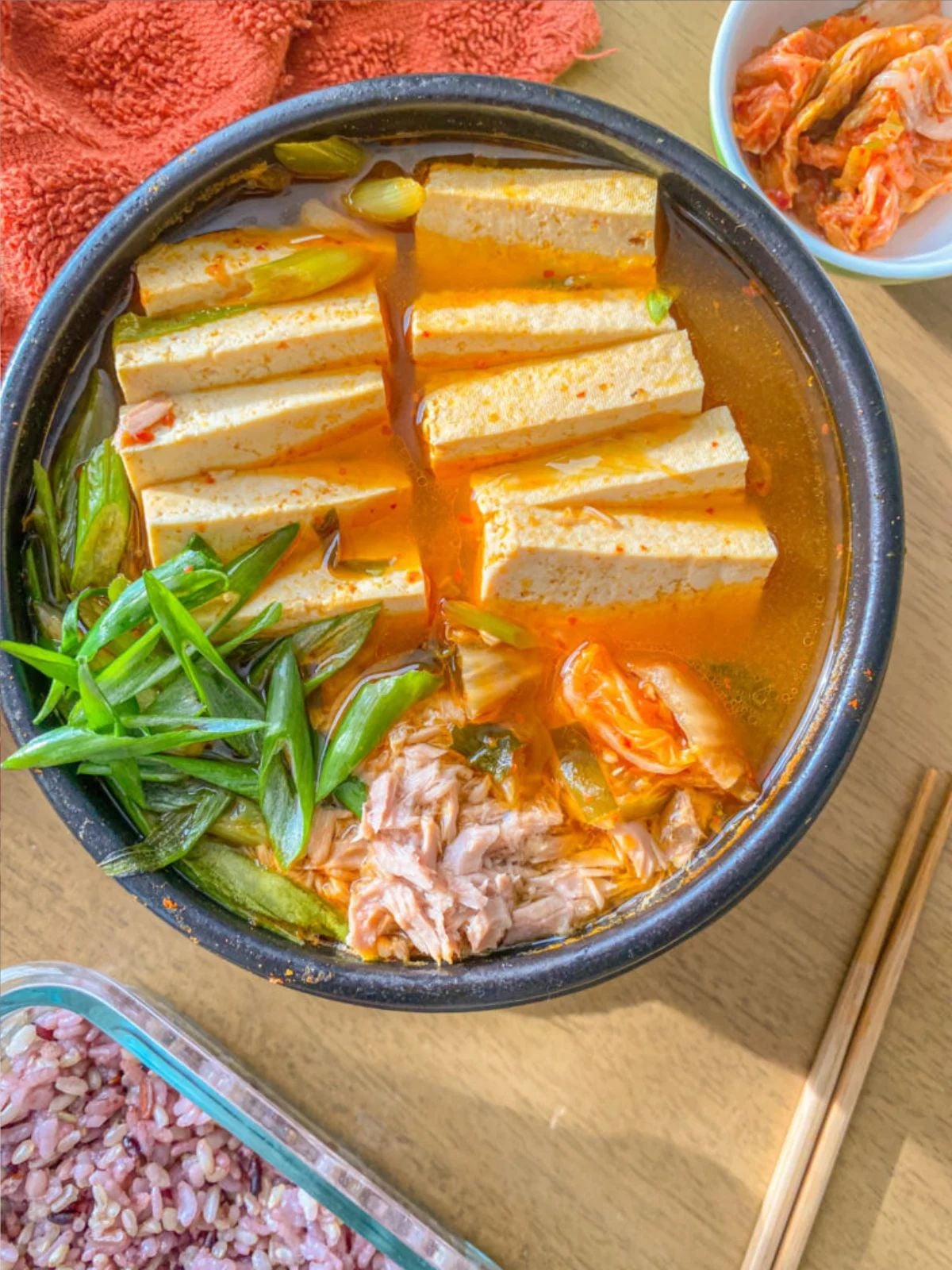 Tofu and kimchi stew with tuna and sliced green onions.