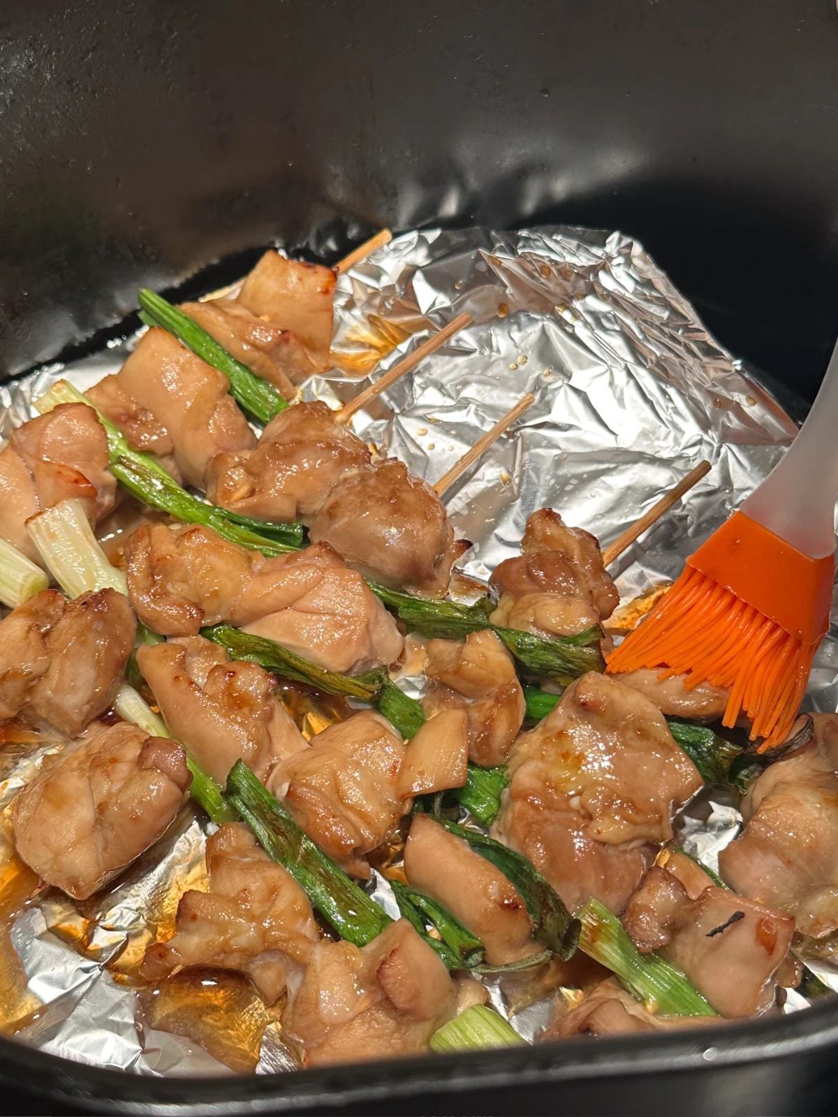 Brushing sauce on chicken skewers in the air fryer.