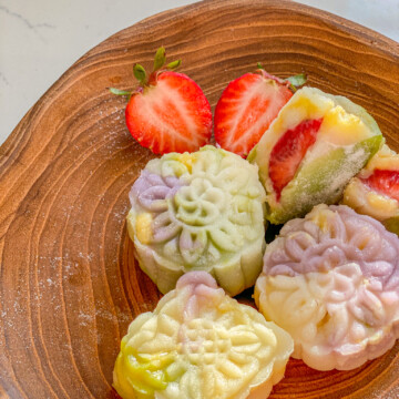 snow skin mooncake mochi filled with custard and strawberry on a wooden plate