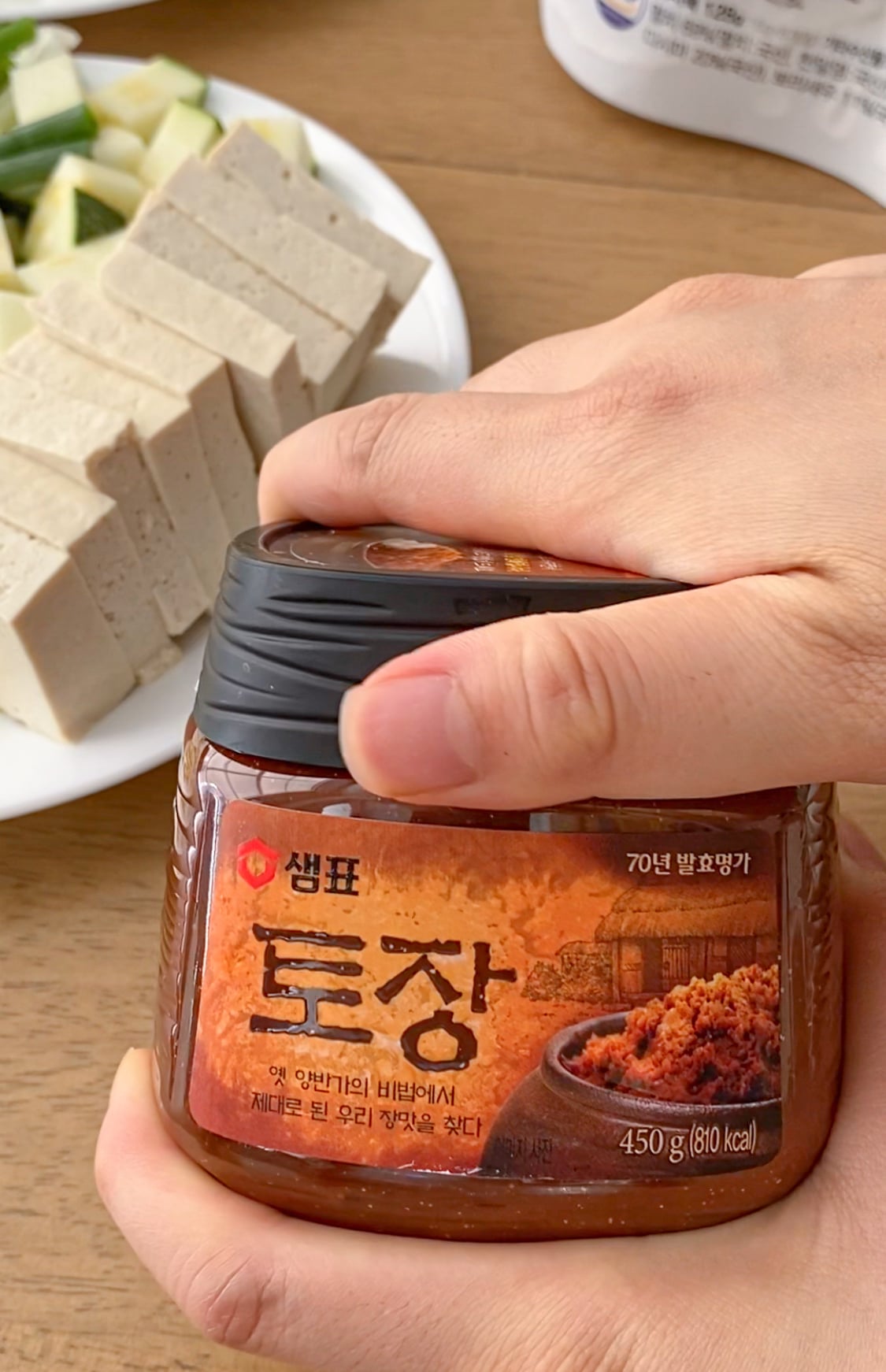 Holding a jar of doenjang.