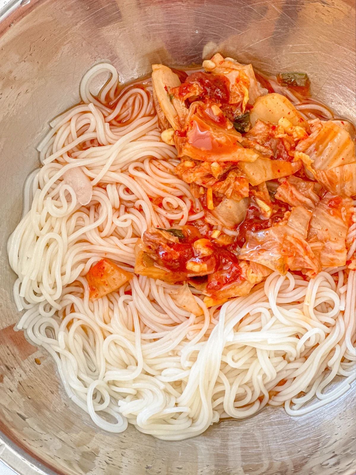 White thin noodles mixed with kimchi and gochujang sauce.