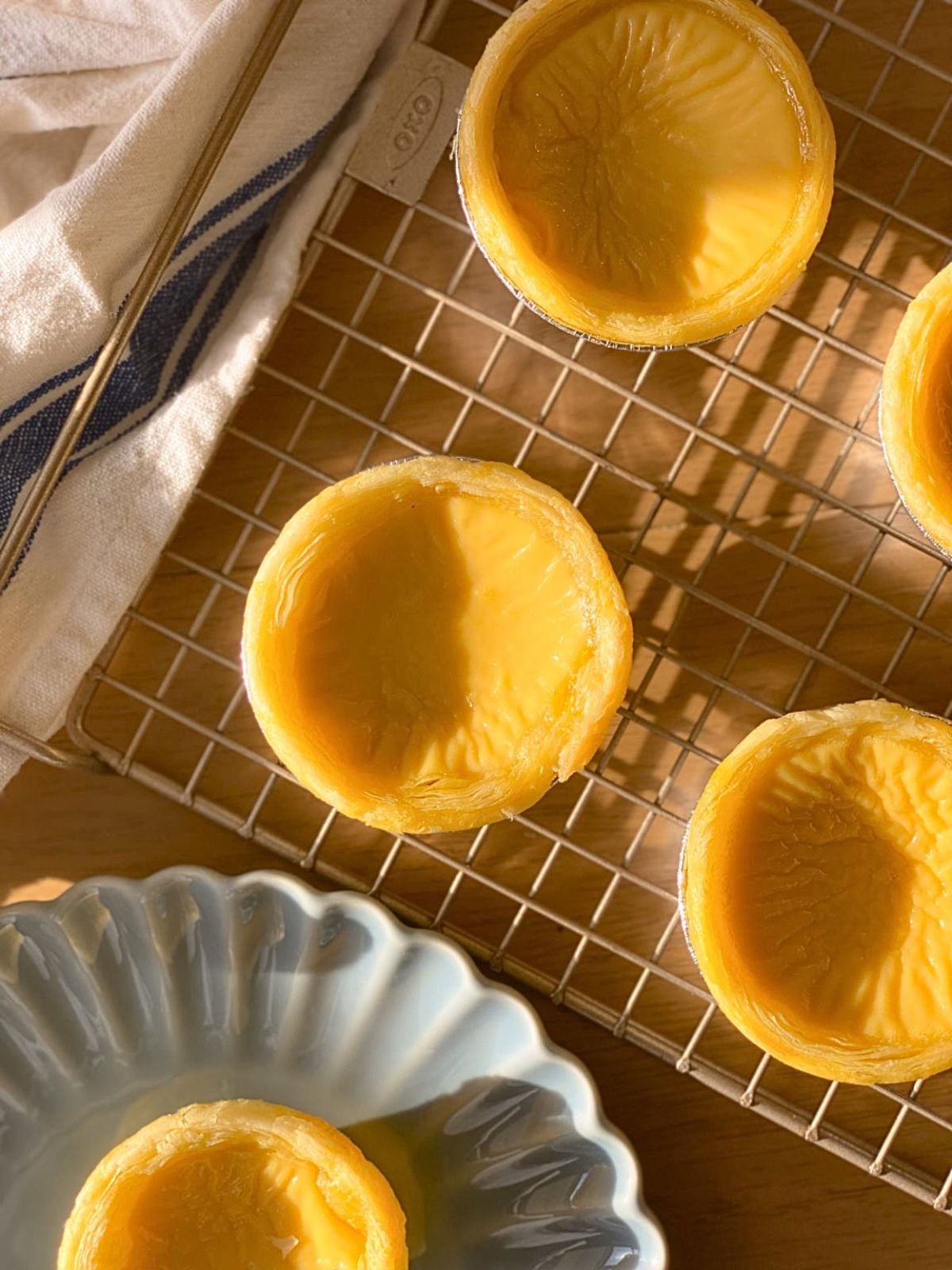 Chinese egg tarts on a plate on and on a wire rack cooling down.