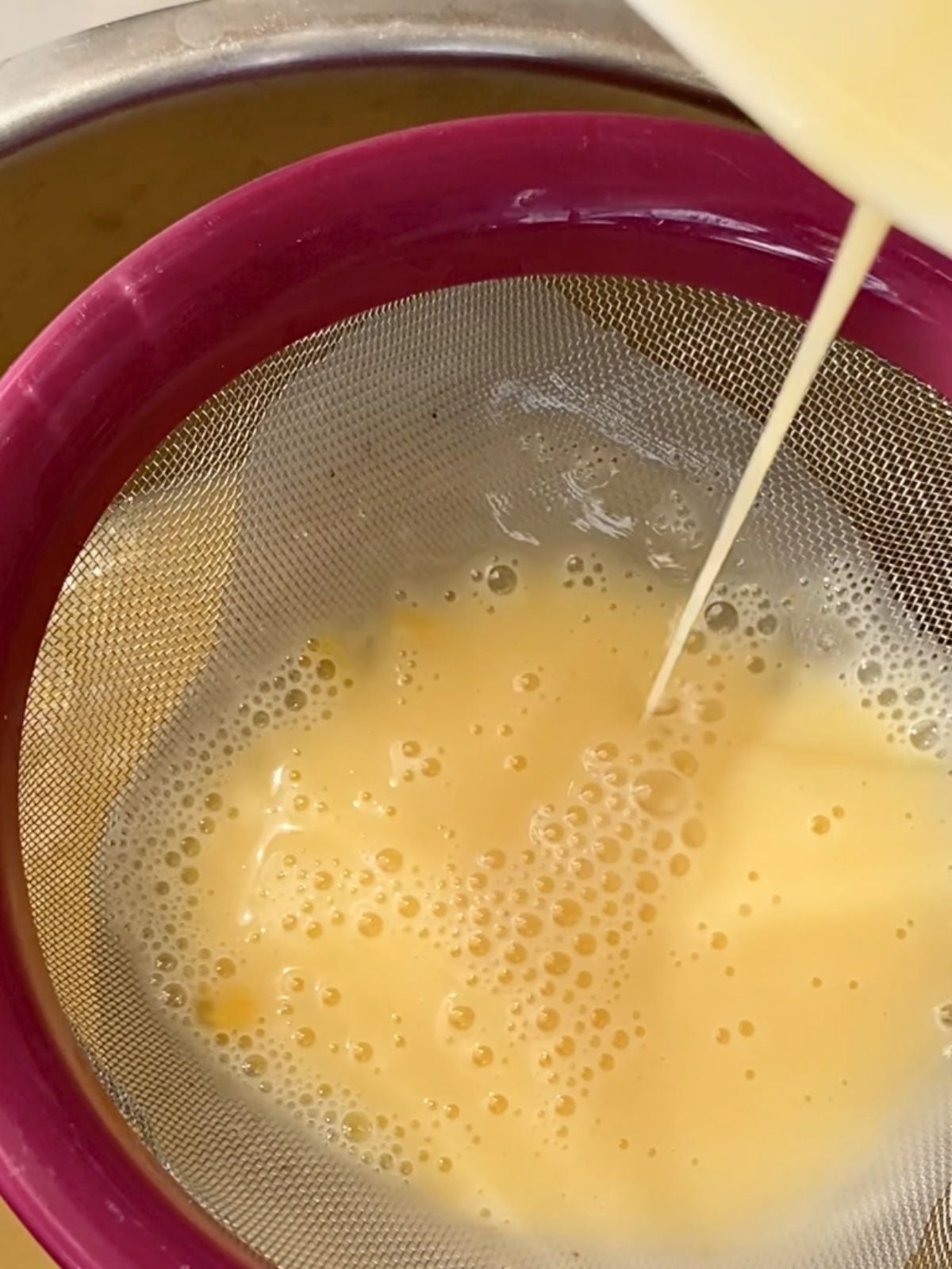 Pouring egg mixture through a strainer.