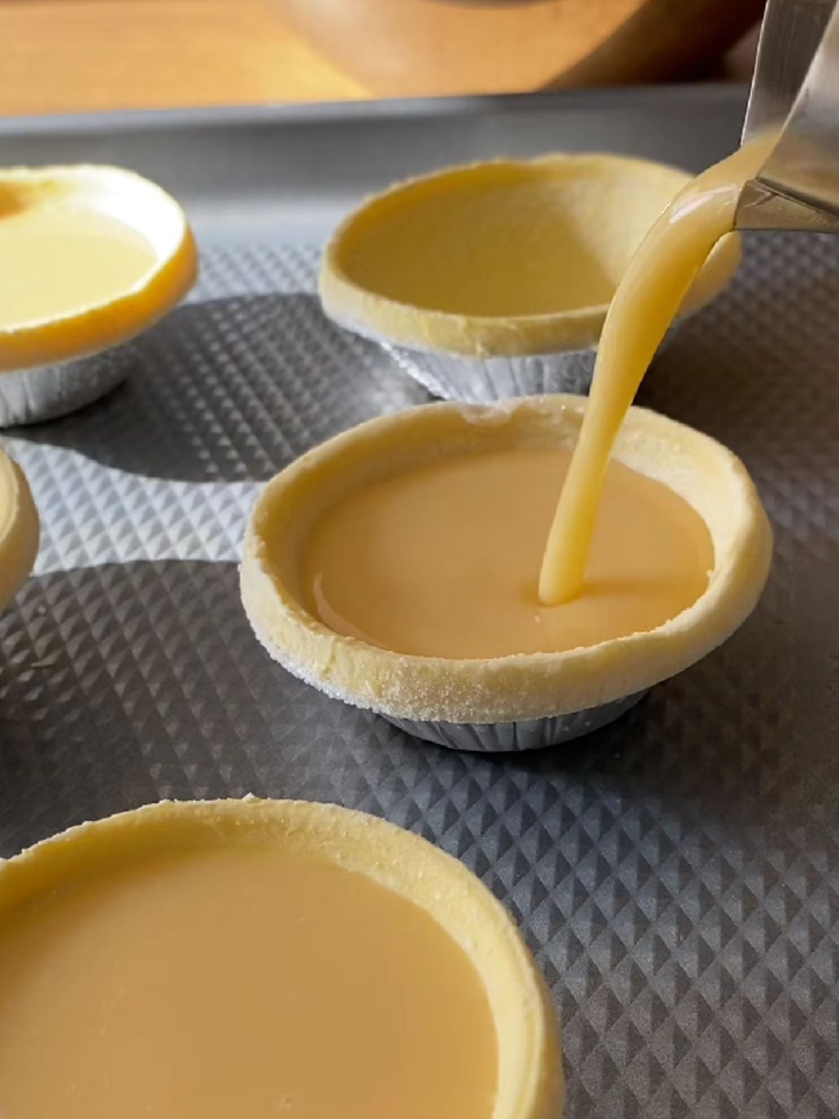 Adding egg mixture in an egg tart shell.