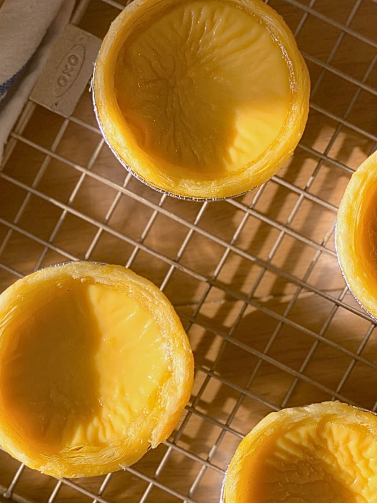 Chinese egg tarts on a wire rack cooling down.