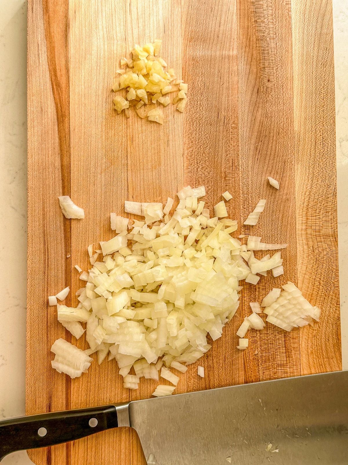 Chopped onions and minced garlic on a cutting board.