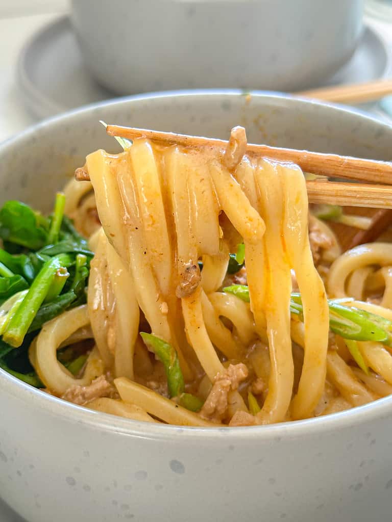 udon noodles in creamy broth with spicy oil spinach