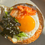 kimchi rice in bowl form topped with sunny side egg, roasted seaweed kimchi and green onions