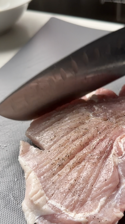 tenderize pork chop with a knife and cutting board