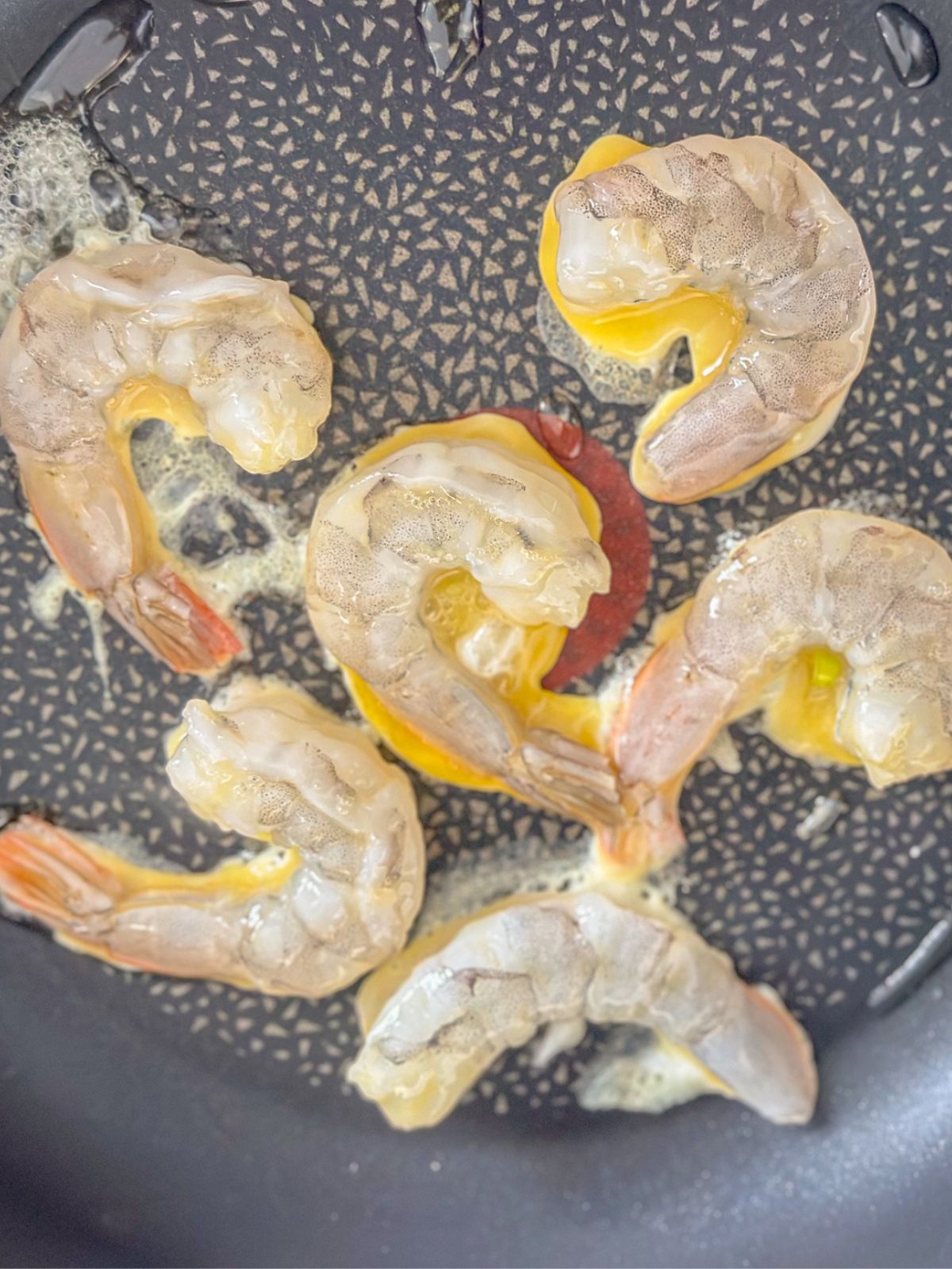 Shrimp sauteed in oil on a pan.