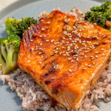 Glazed salmon on top of rice and broccoli.