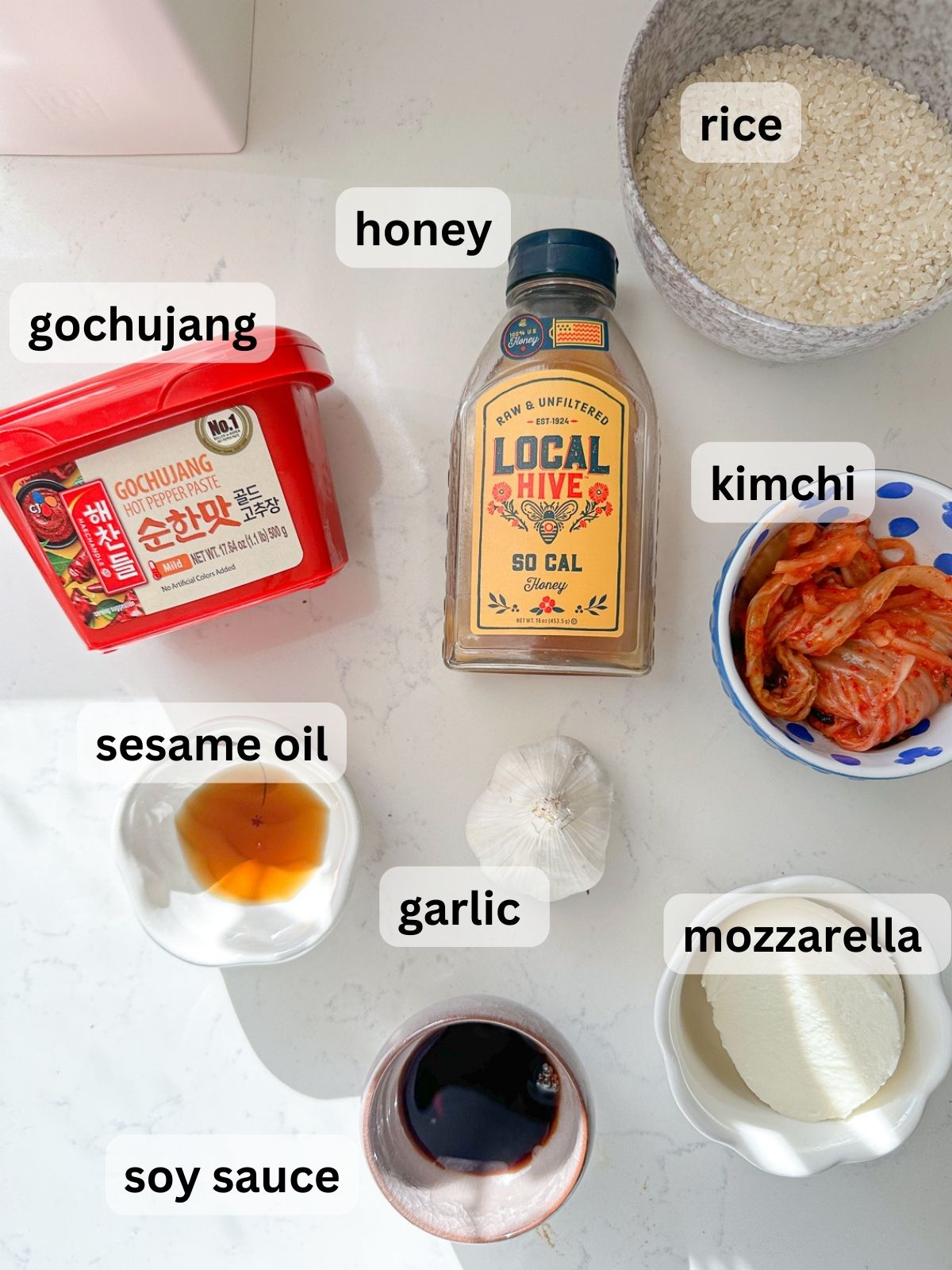 Gochujang, honey, rice, kimchi, mozzarella, garlic, soy sauce, sesame oil arranged in bowls.