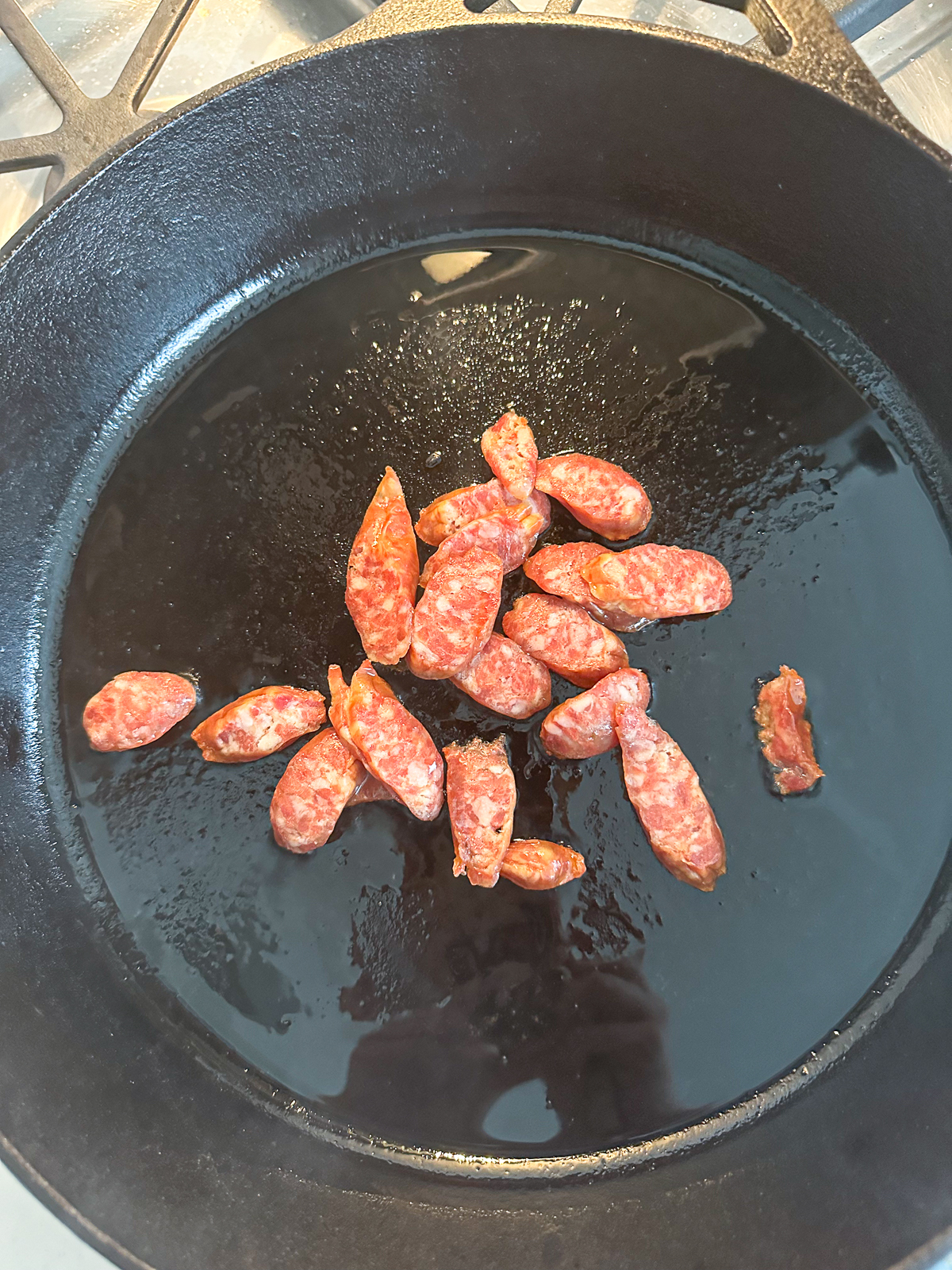 Frying chinese sausage in a black pan.
