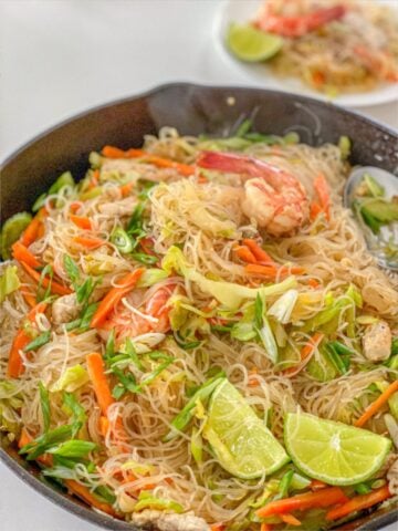 Noodles with celery, carrot, cabbage, onion, shrimp and pork in a pan.