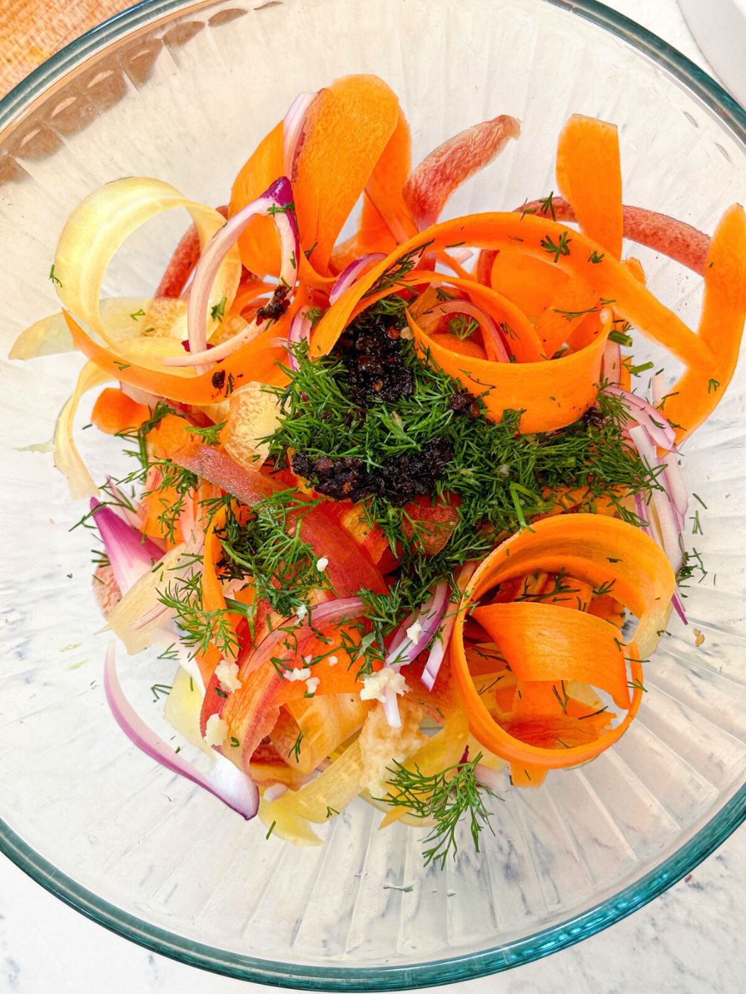 A bowl of Carrot salad with red onion, dill, carrots, and grated garlic.
