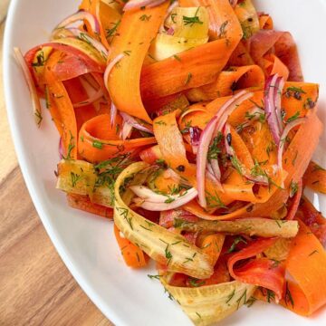 A plate of Carrot salad with sliced onions and chopped dill.