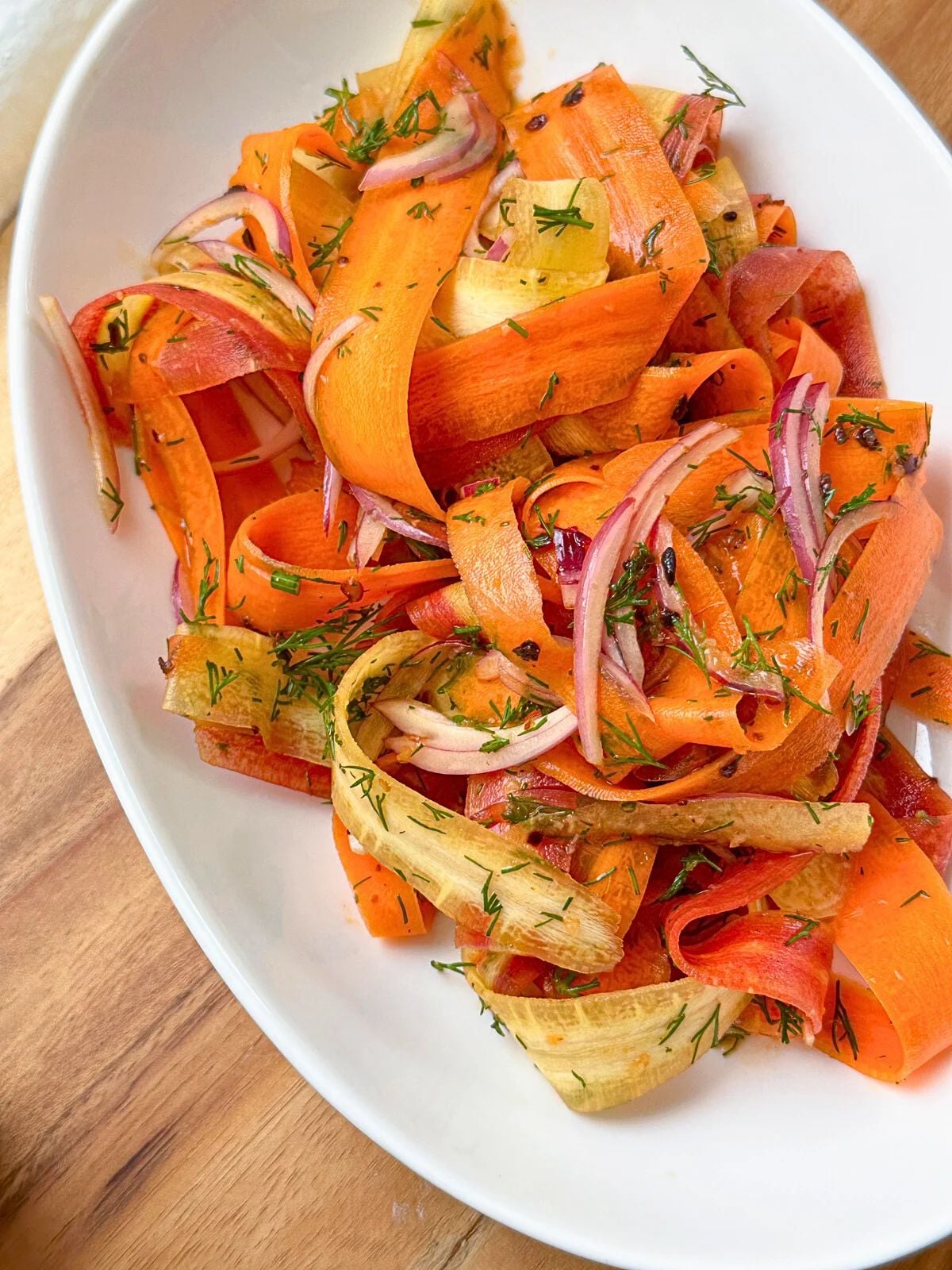 A plate of Carrot salad with sliced onions and chopped dill.