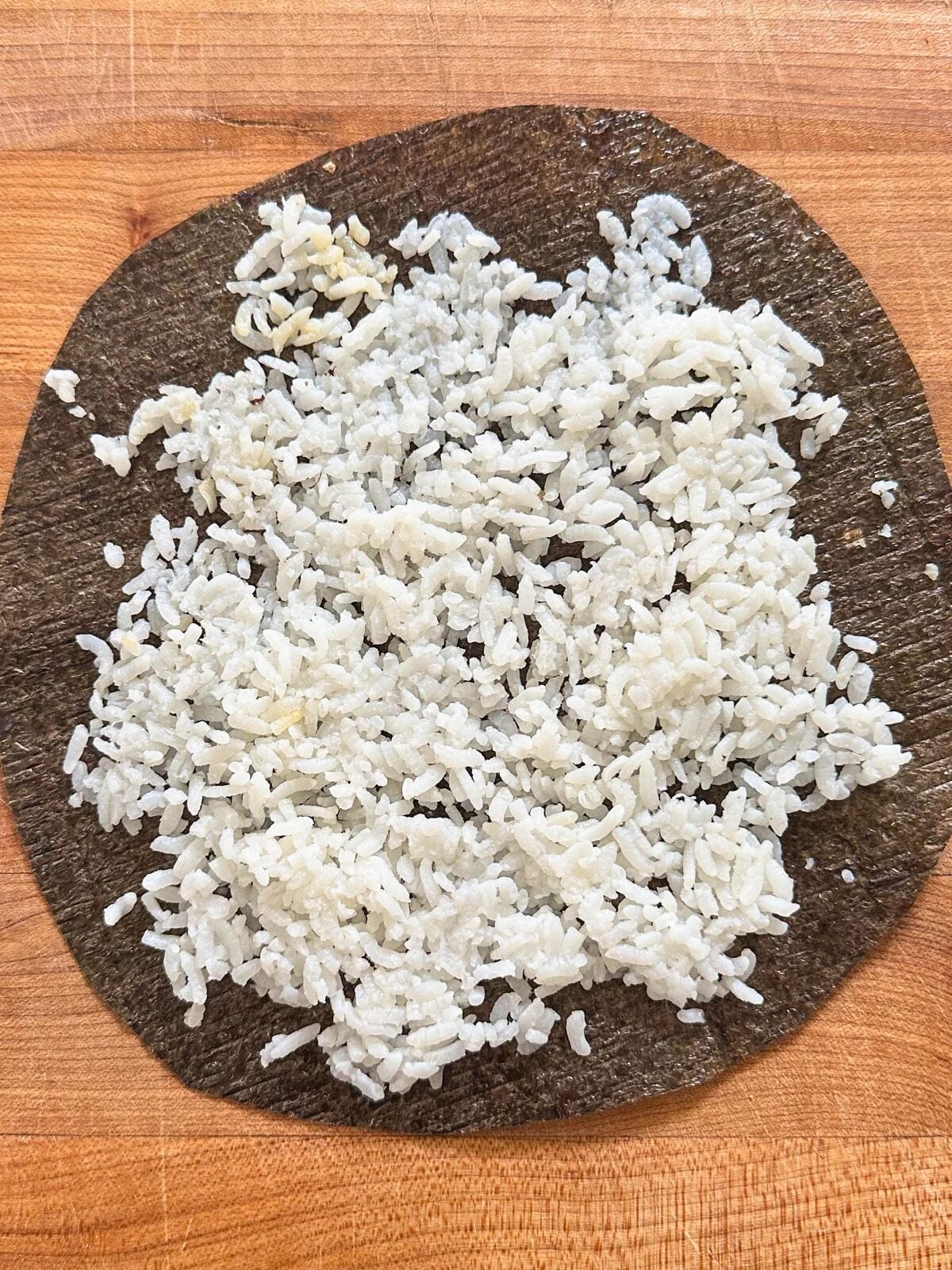 Cooked white rice spread evenly on a piece of seaweed (Nori).