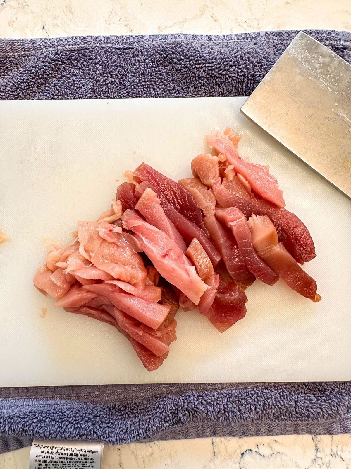 Chopped Tuna on a cutting board with a kitchen towel underneath and a kitchen knife on the side.