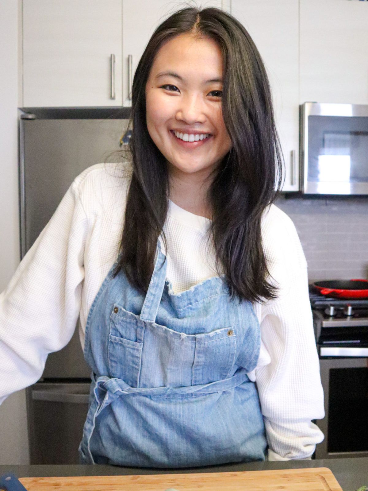 Dark hair asian girl with blue apron in a kitchen.