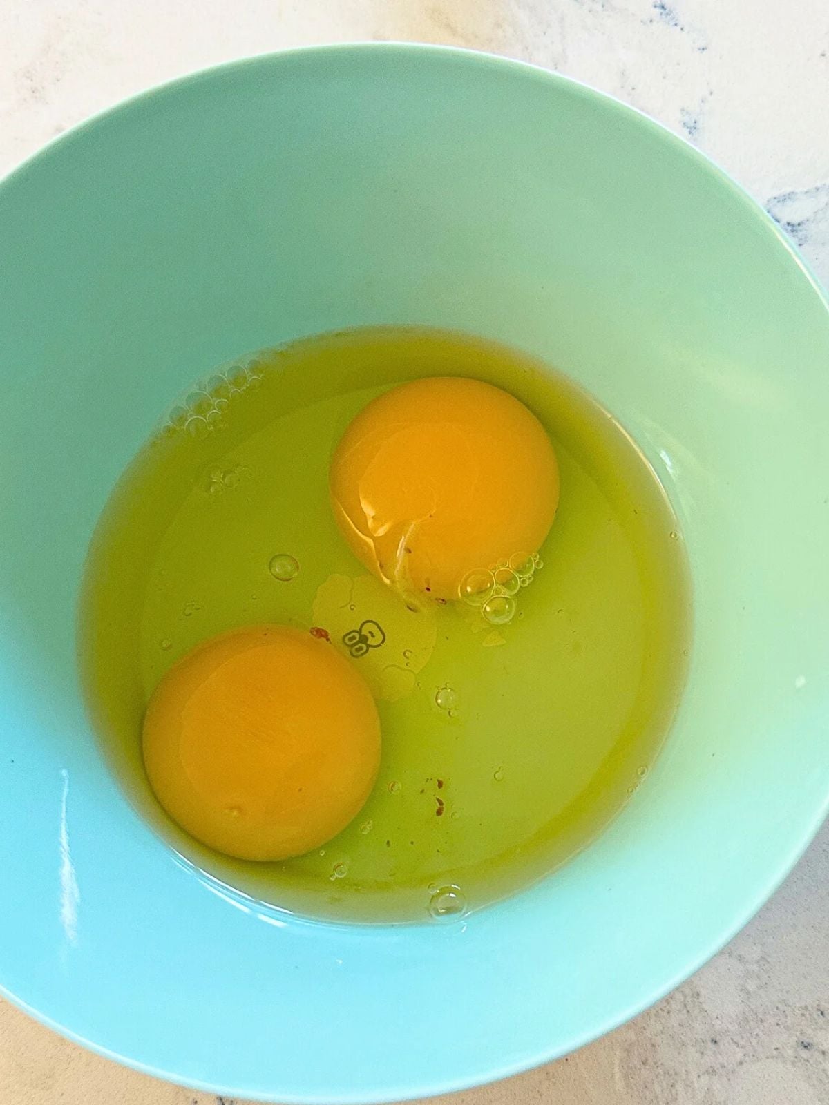 Two raw eggs in a bowl.