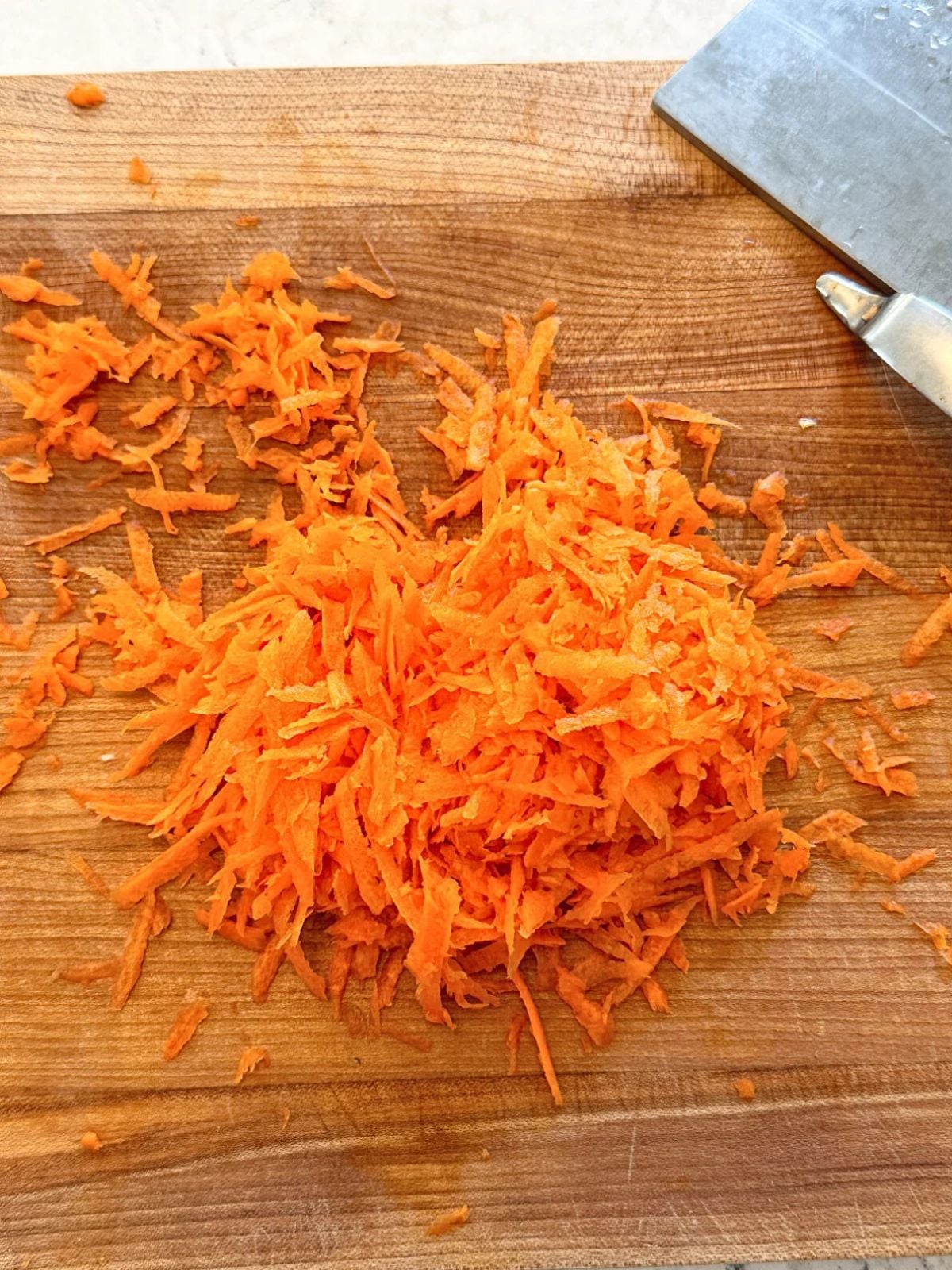 Grated carrots on a wooden chopping board.