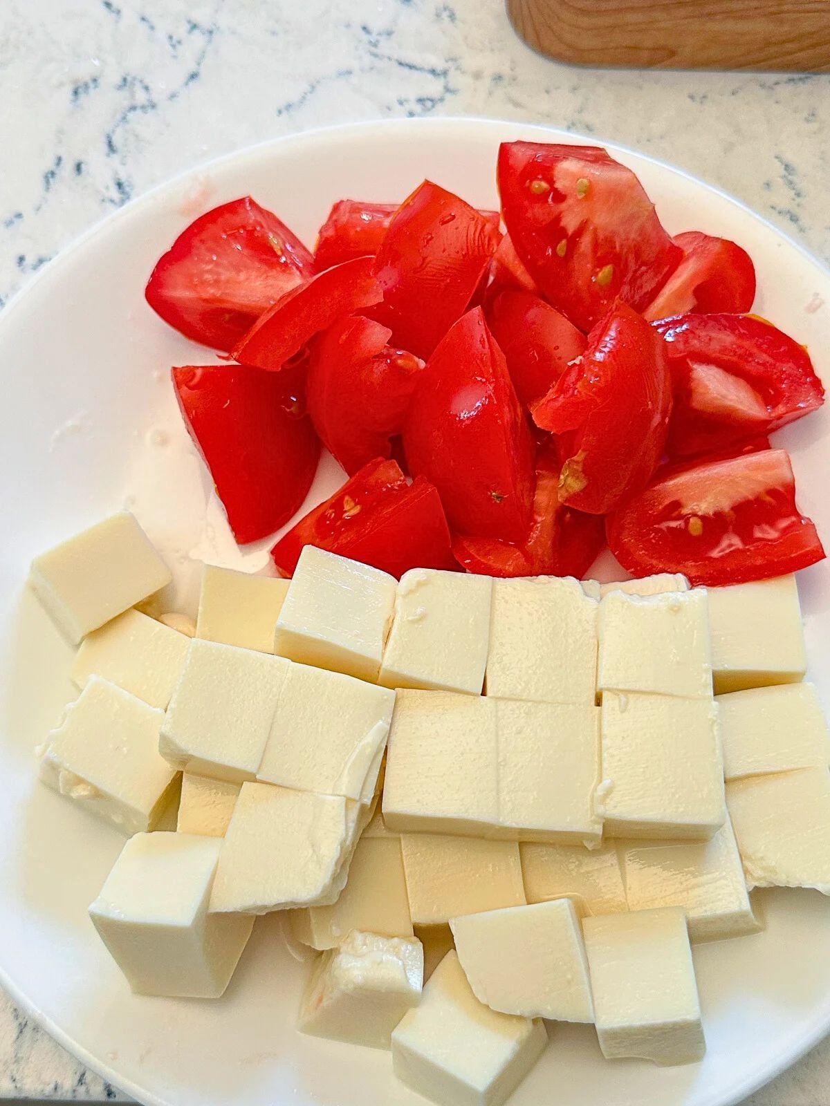 A plate of chopped tofu and fresh tomato chunks.