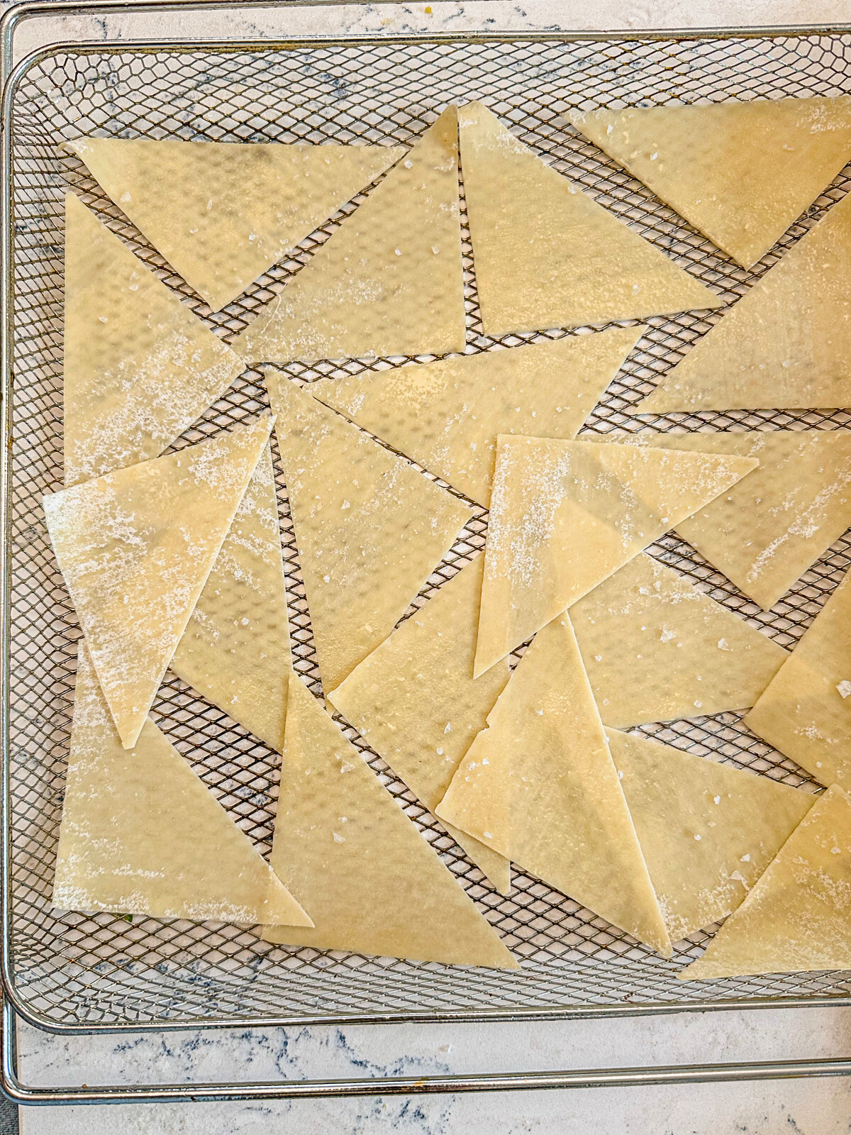Wonton in triangular shapes placed in a baking tray.