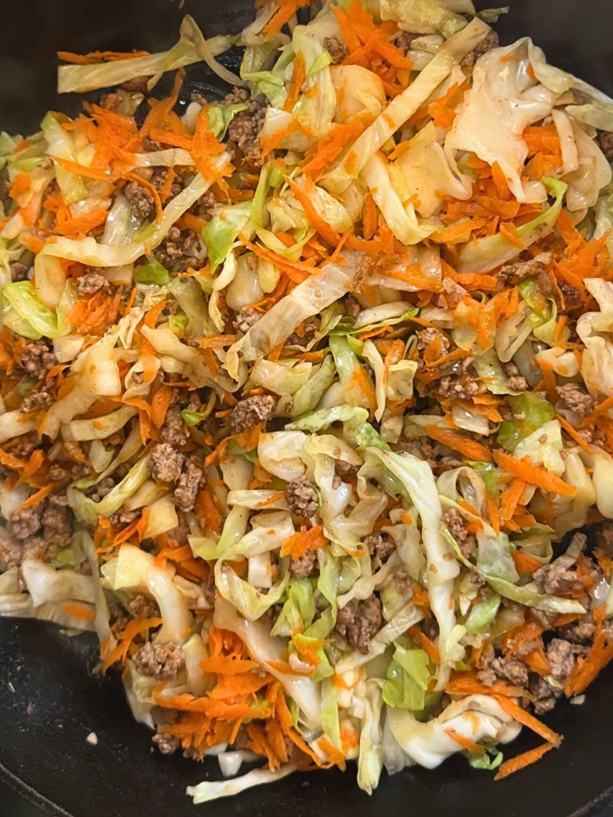 Cooked ground pork with mixed vegetables in a pan.