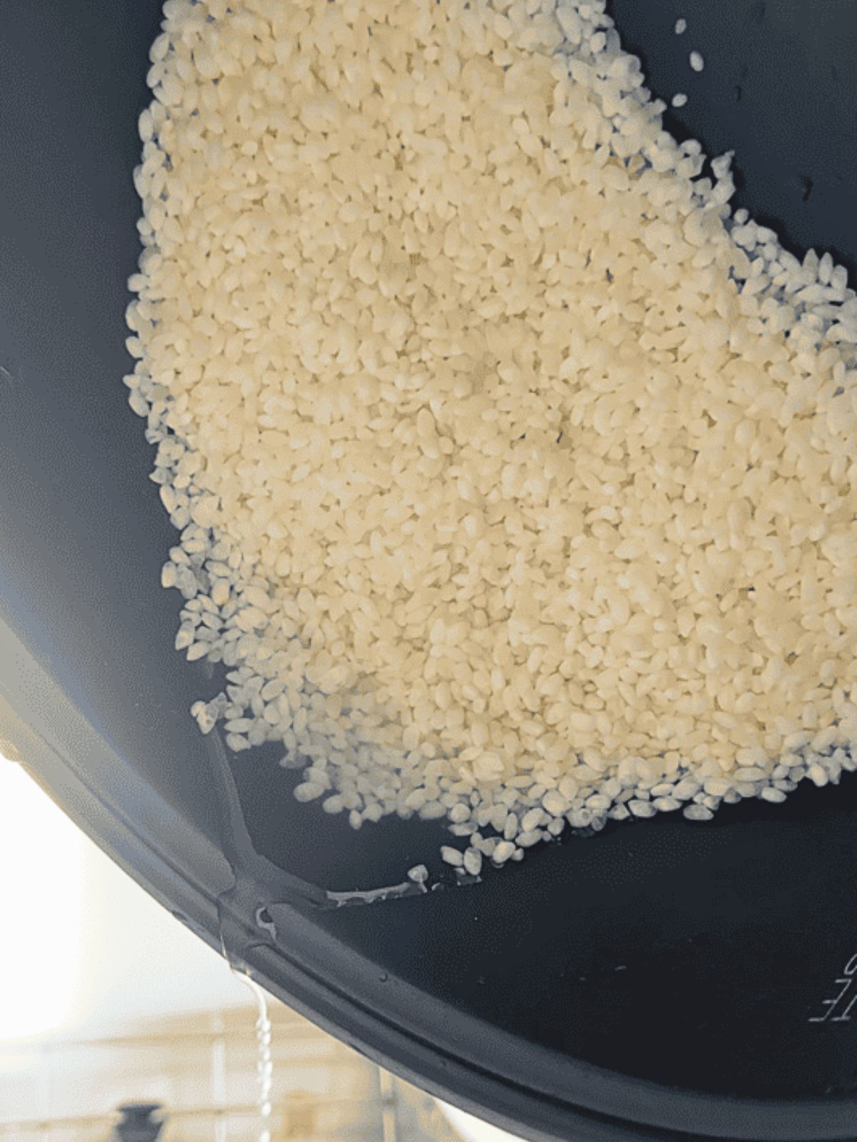 Pouring out the water from the soaked rice in the pot.