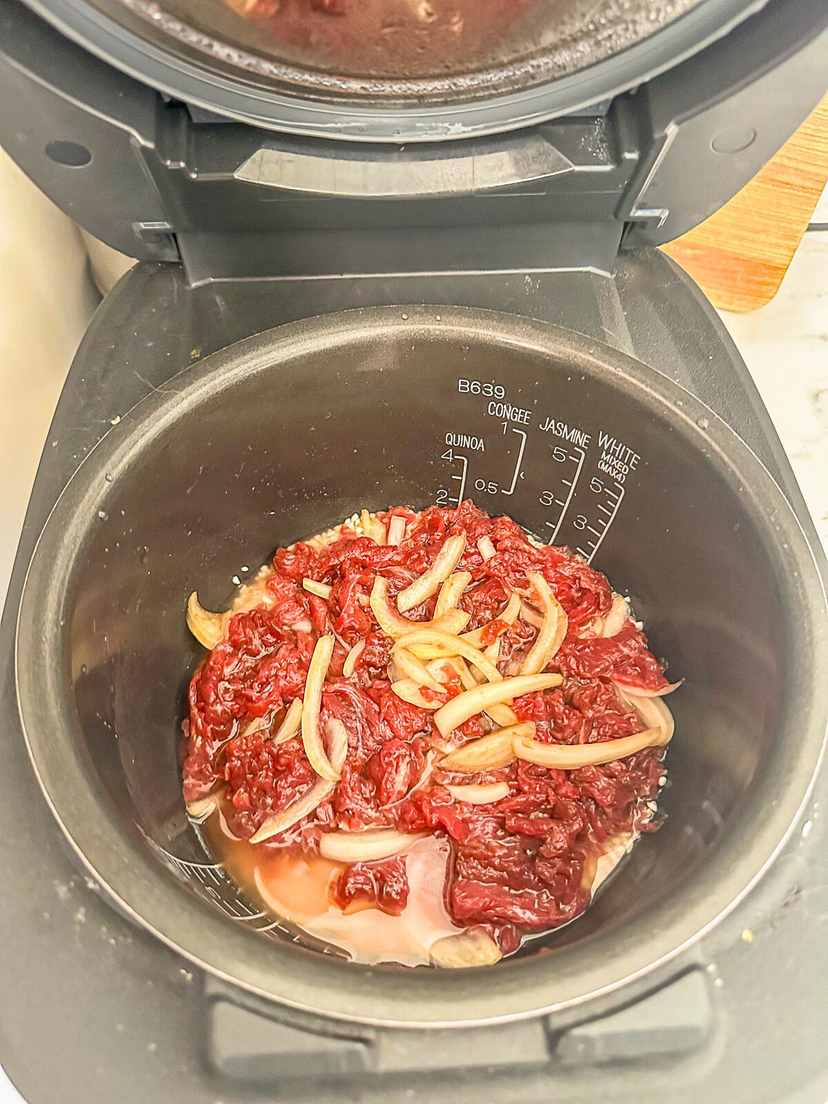 Placed pot in the rice cooker with marinated beef with white onions. 