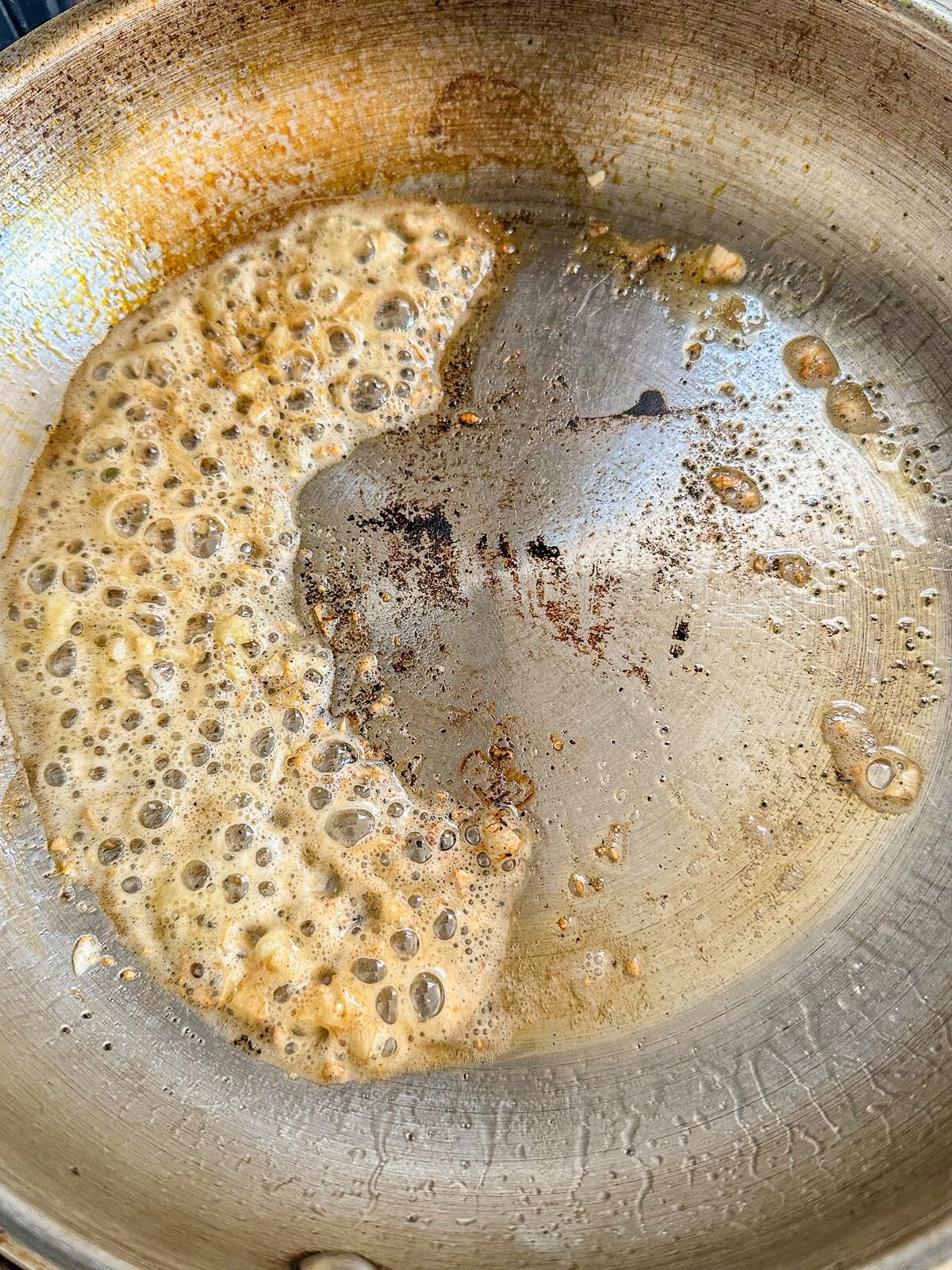 Melted butter with galic bits simmering on a pan.