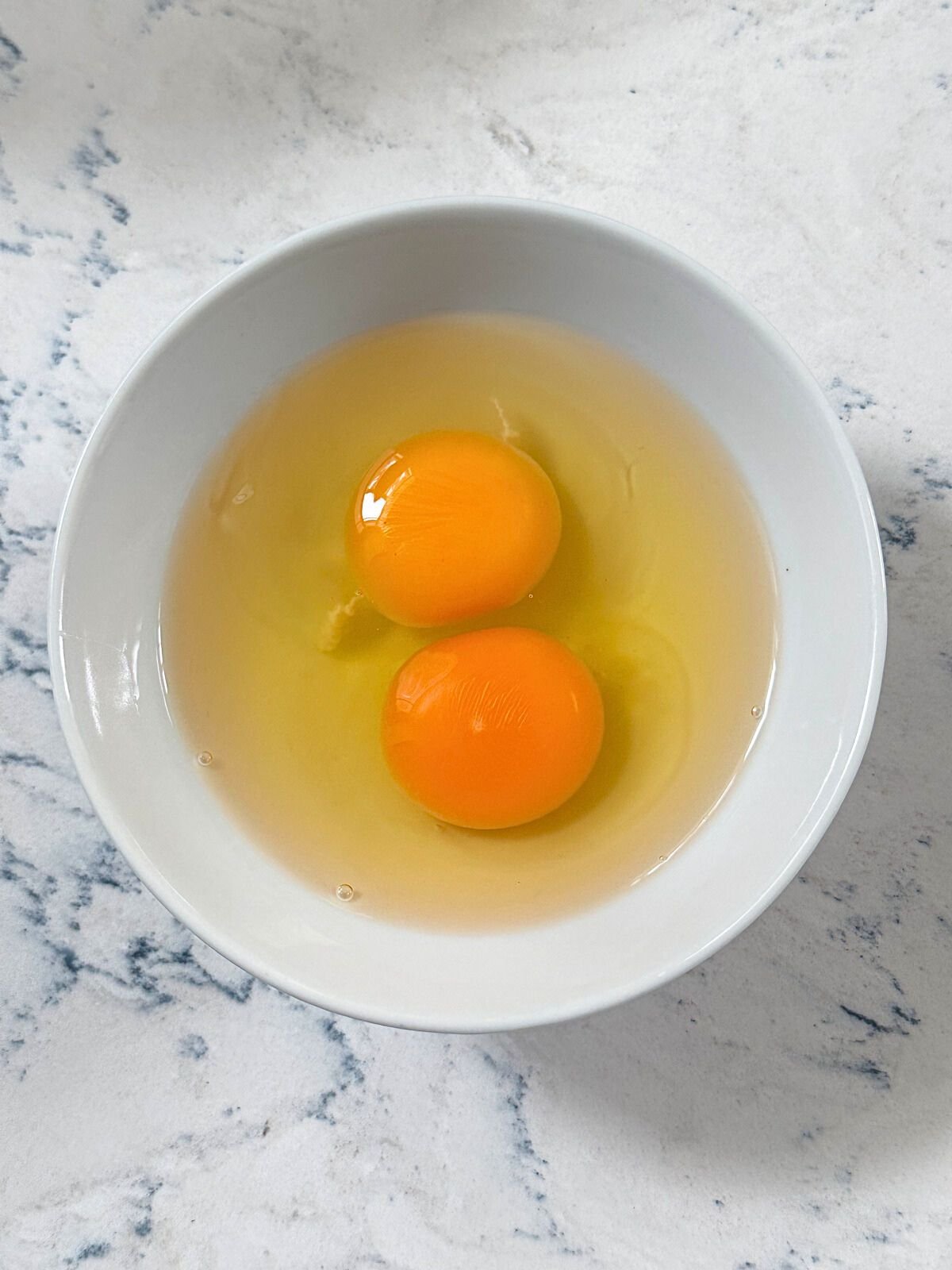 Two raw eggs in a small bowl.