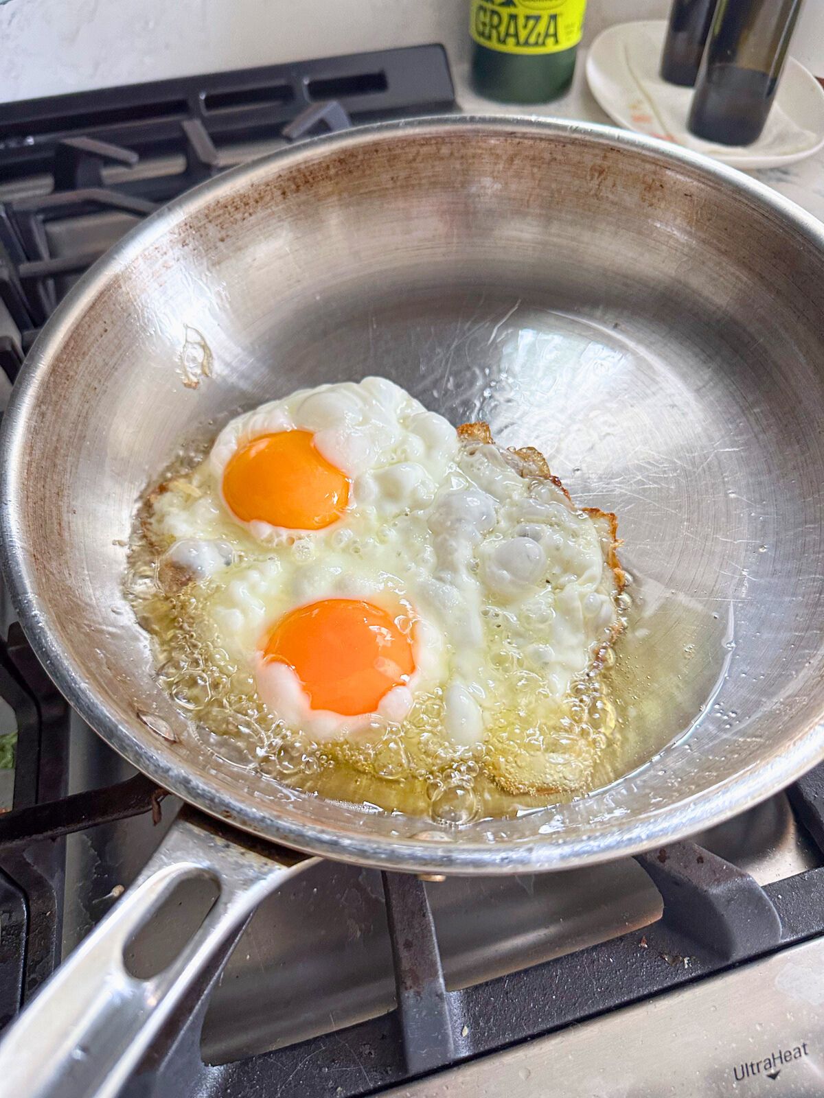 Two eggs sizzling in hot cooking oil in a pan.