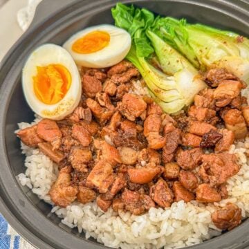 A bowl of minced pork served over rice, paired with a soft-boiled eggs and fresh bok choy on the side.