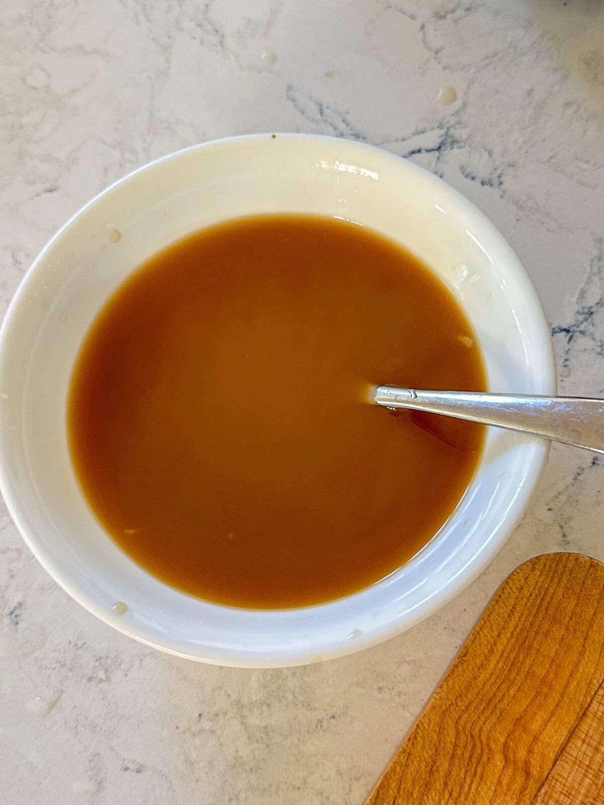 A bowl of garlic sauce with a spoon on the side.