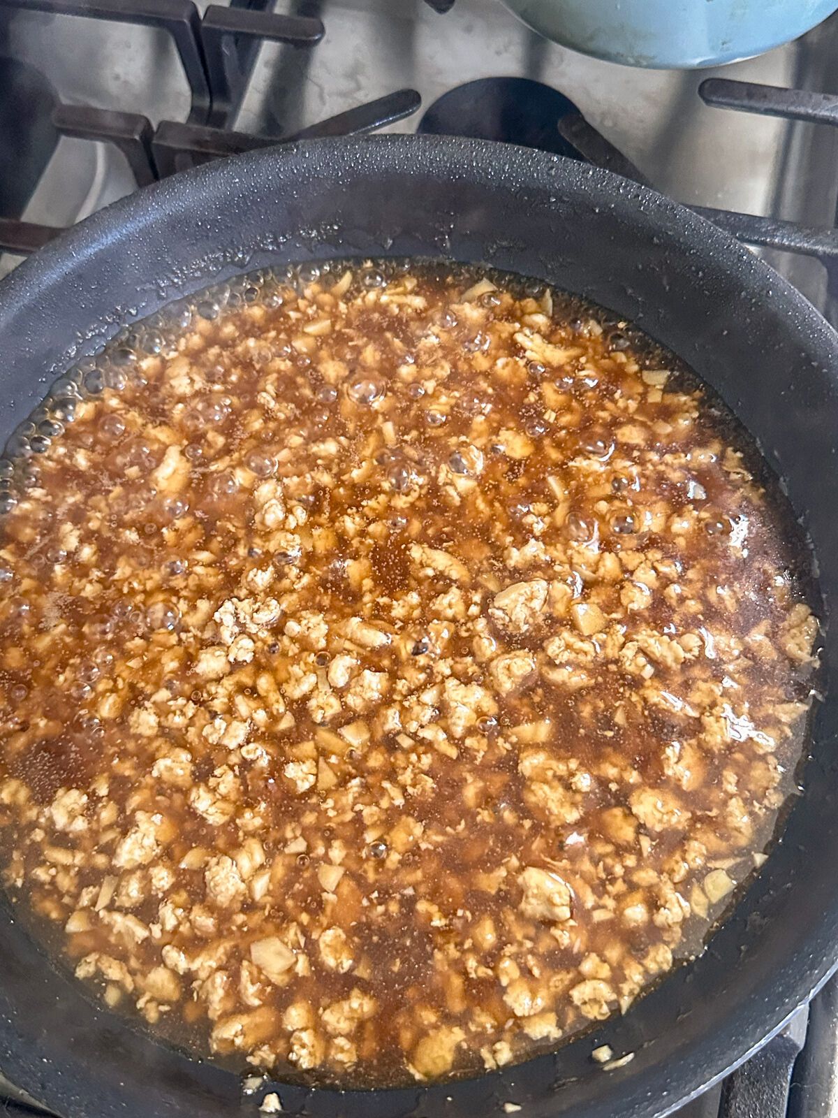 Simmering ground meat in a pan with garlic sauce.