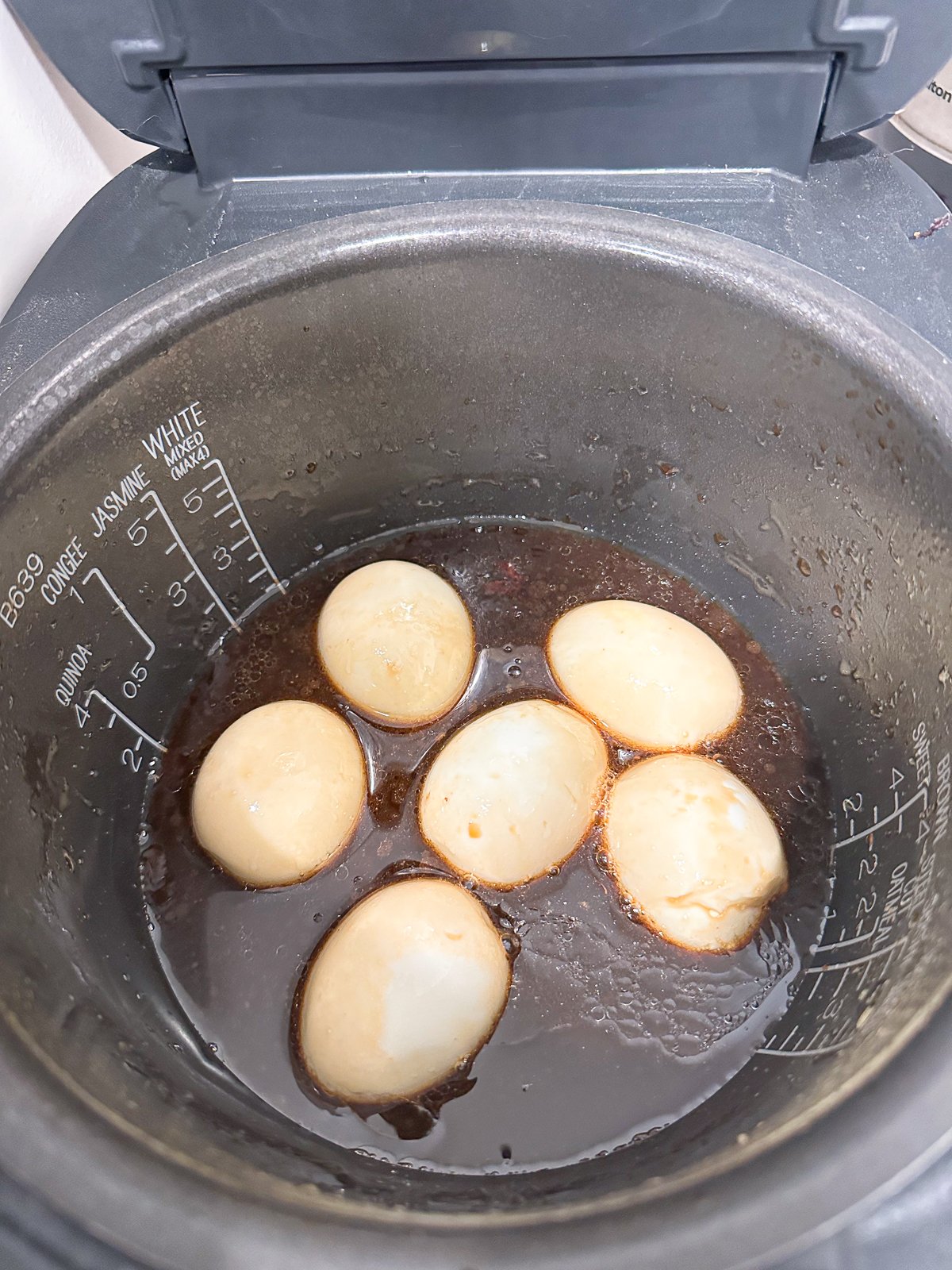 Six boiled eggs in a pot filled with soy sauce.