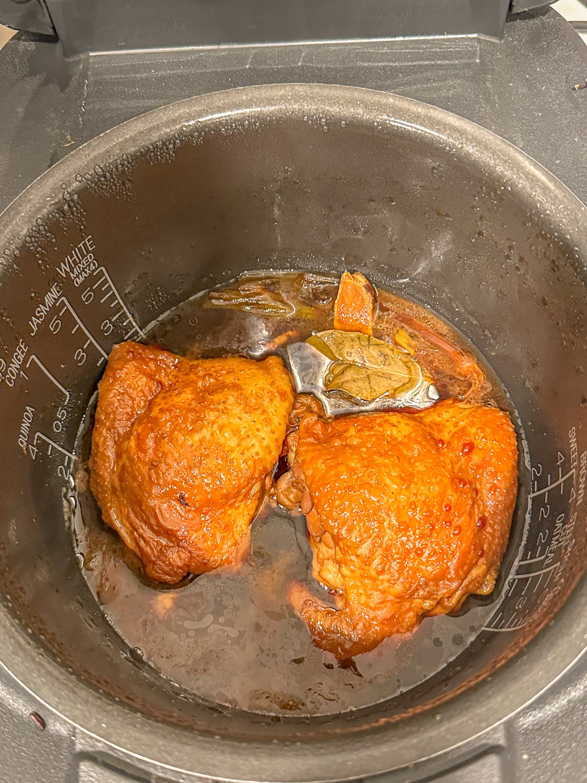 Cooked chicken inside a pot filled with soy sauce.