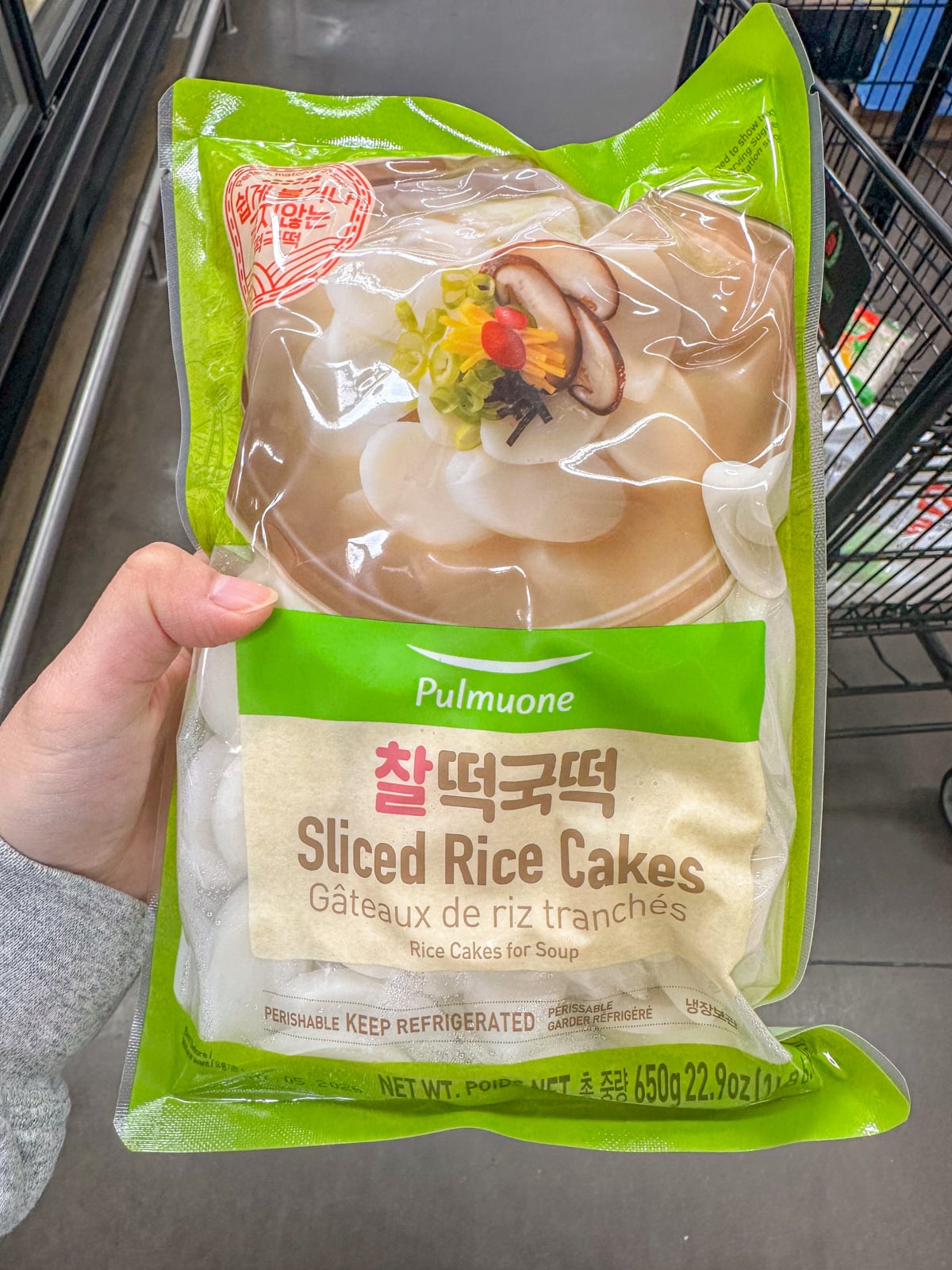 Holding a pack of uncooked sliced rice cakes.