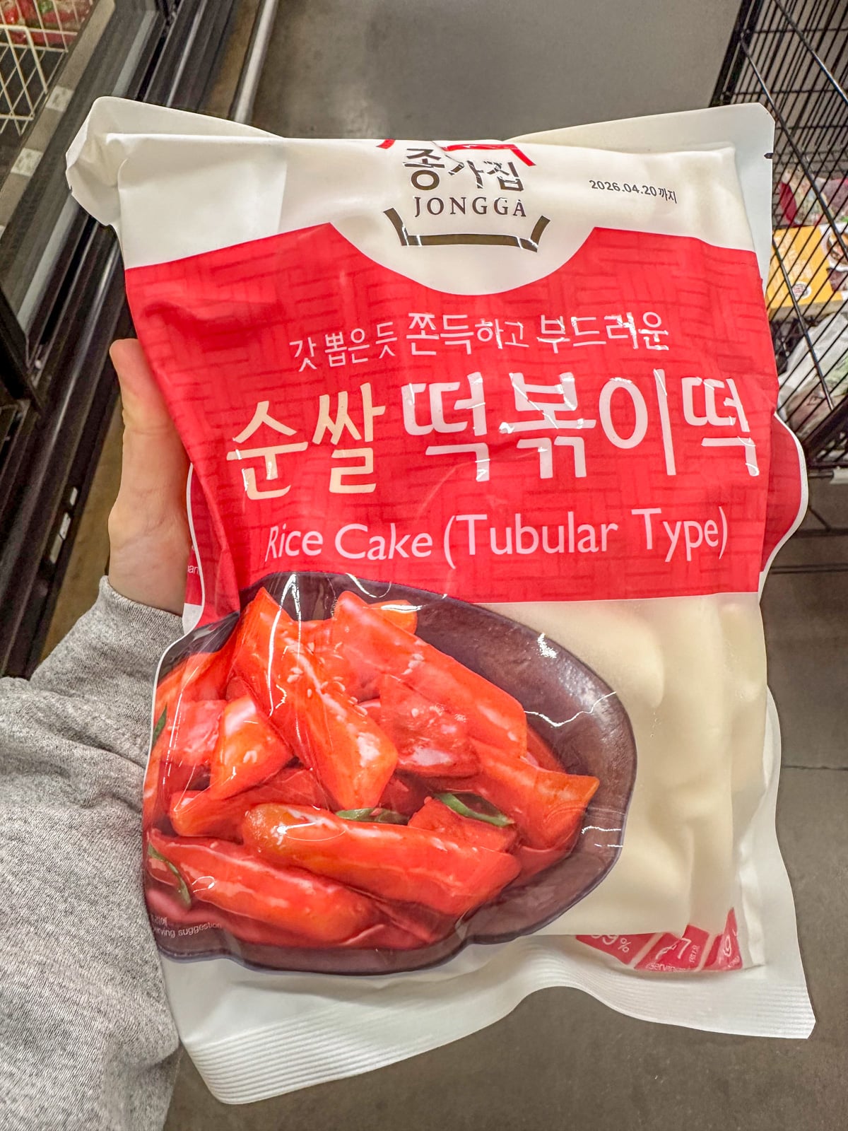 Holding a pack of uncooked tubular rice cakes.