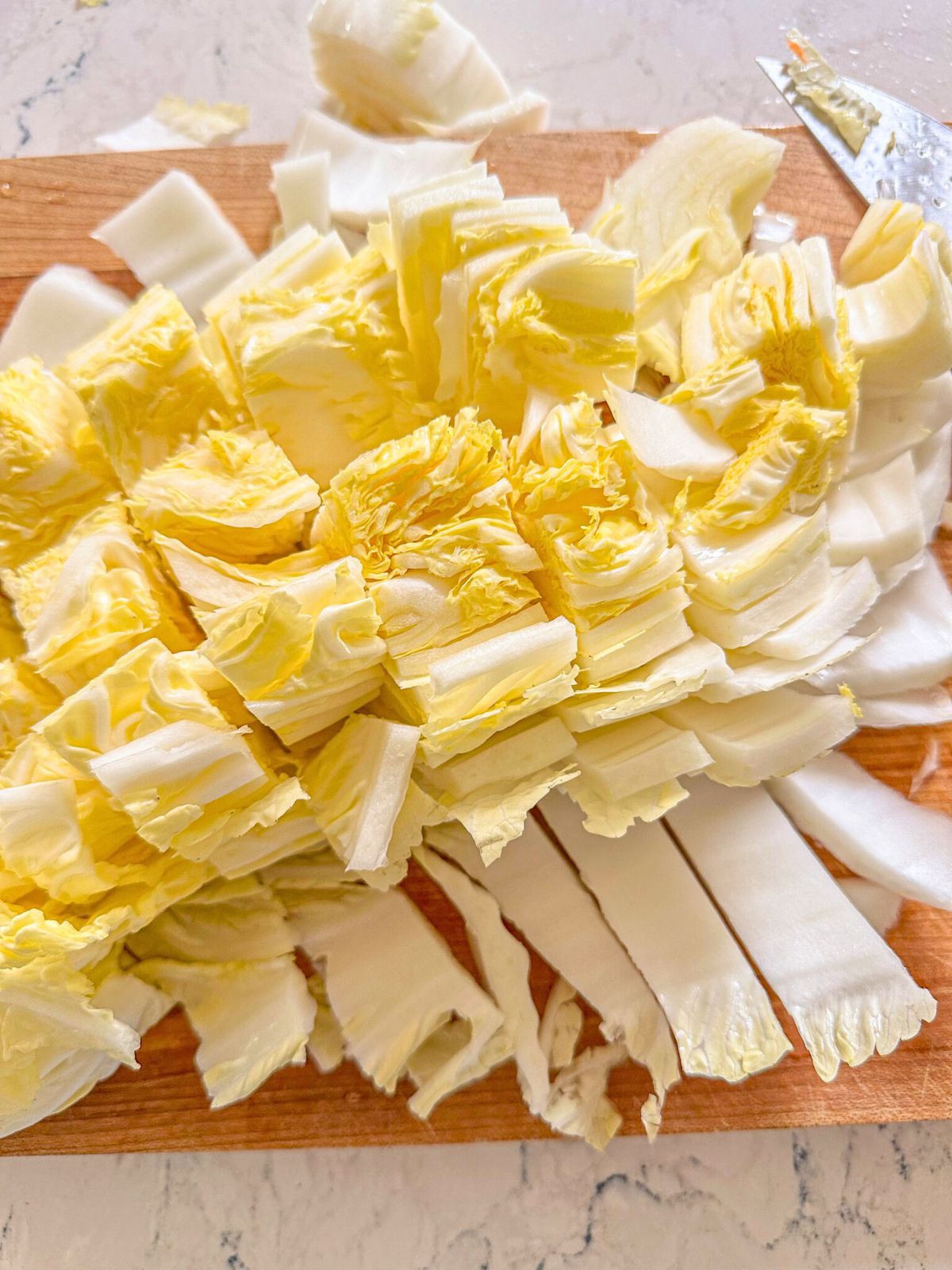 Chopped nappa cabbage on a wooden chopping board.