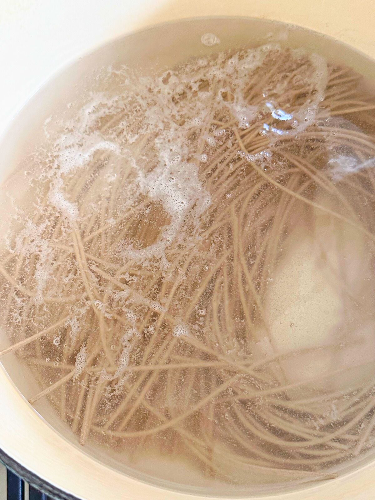 Soba noodles boiling in a pot of water.