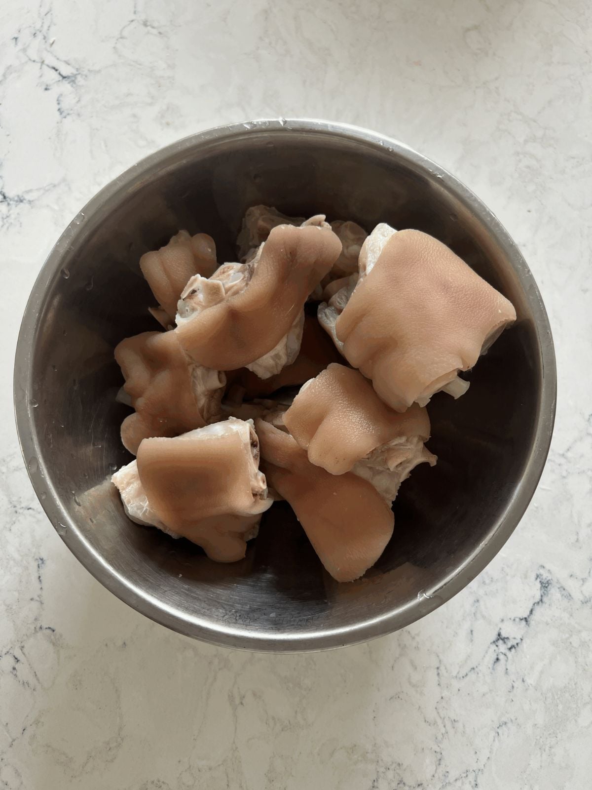 Boiled pork knuckles in a metal bowl.