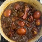 Pork knuckles and peeled eggs boiling in Chinese vinegar sauce in a large pot.