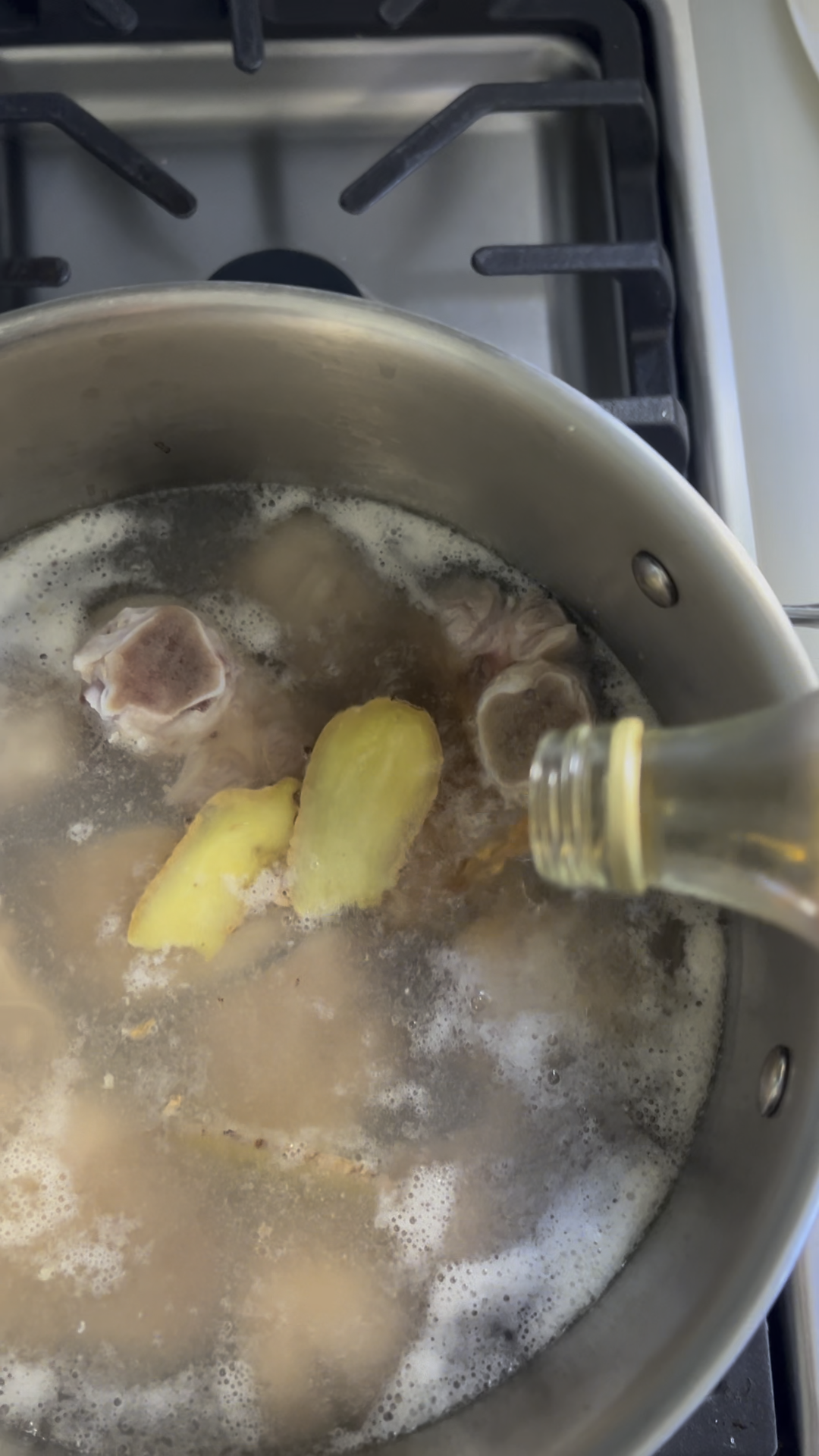 Pork knuckles in a pot of water with ginger slices and vinegar added.