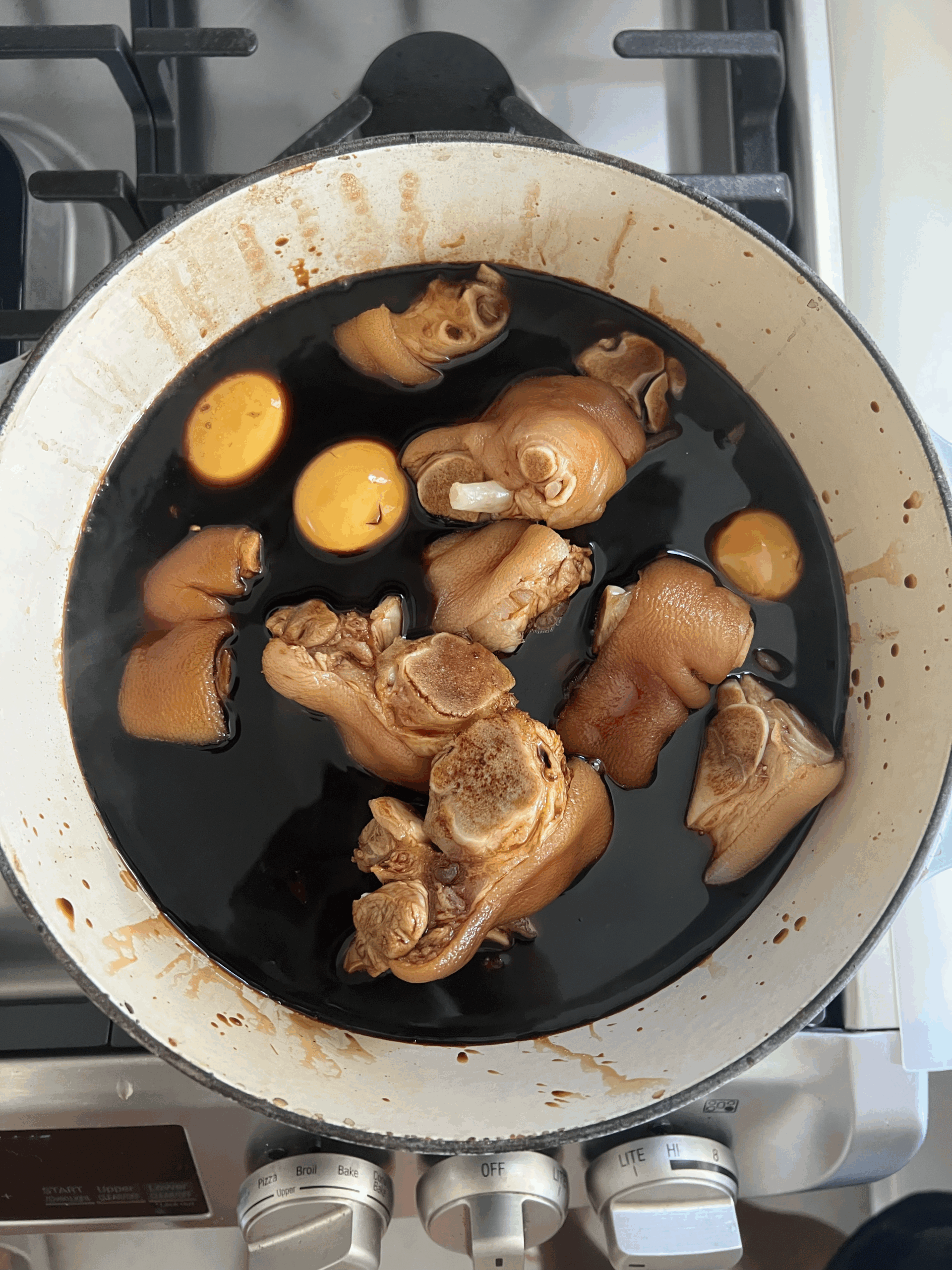 Pork knuckles and peeled eggs soaking in Chinese vinegar sauce in a large pot.