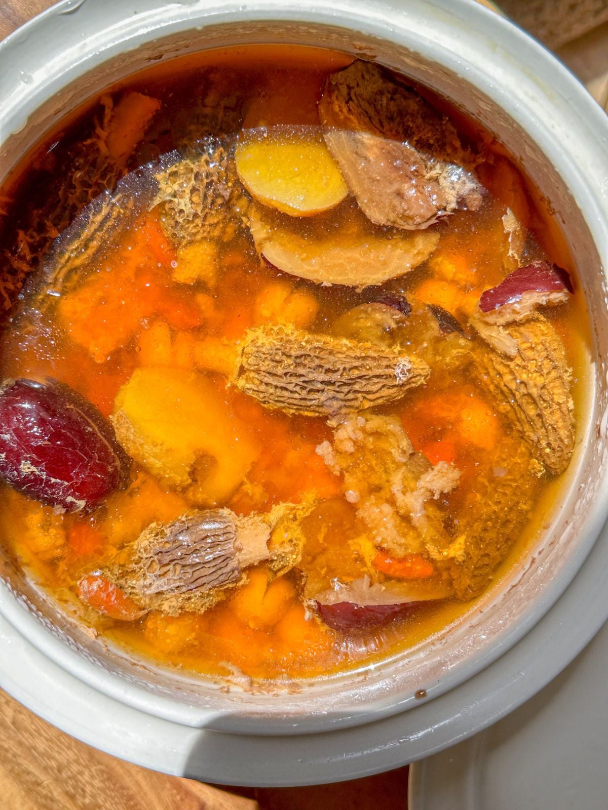A pot of cooked Chinese postpartum soup with tender pork, mushrooms, jujube, ginger, and Chinese herbs.